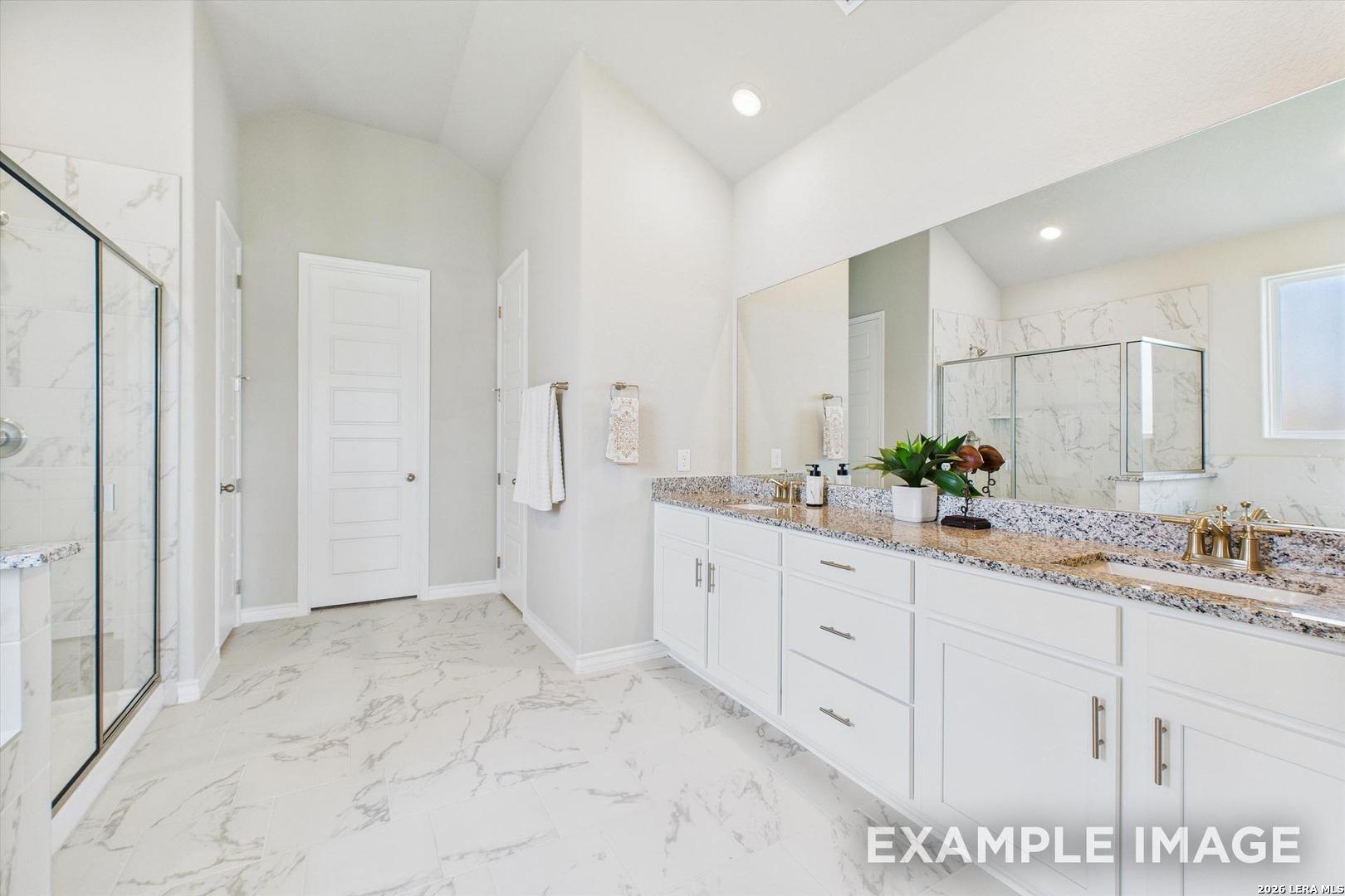 Primary bathroom with dual vanity, granite countertops, and walk-in shower in The Foster F plan, Potranco Oaks, Castroville.