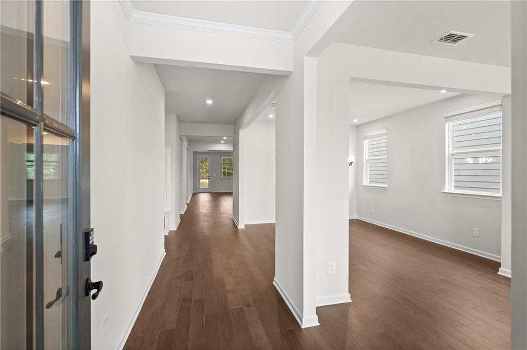 Elegant hallway with hardwood floors, arched openings, and sheer window blinds in Davidson Homes The Glenwood A, Loganville, GA