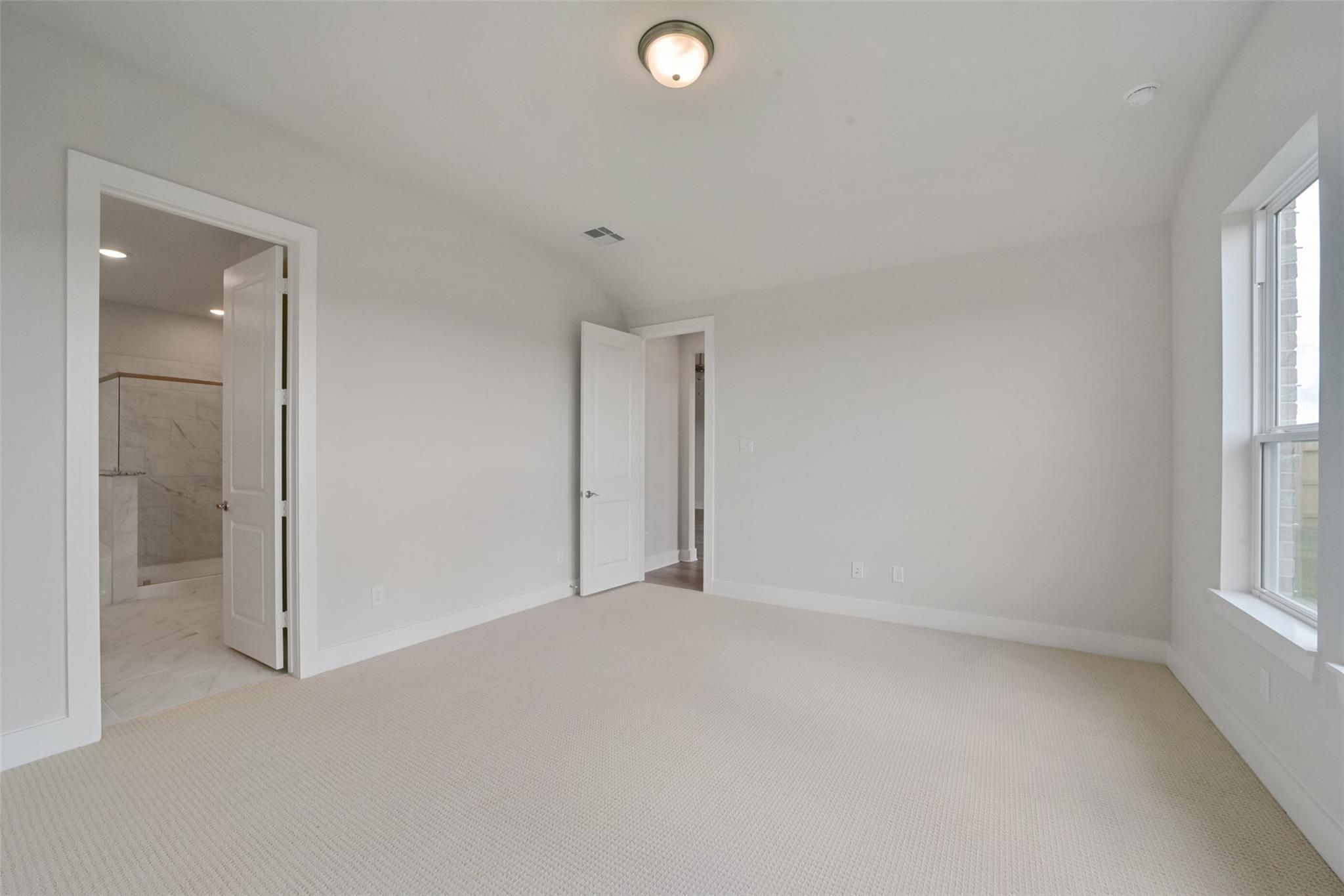 Bright secondary bedroom with en-suite bath, beige carpet, and large window in Davidson Homes The Zion A, Lago Mar, Texas