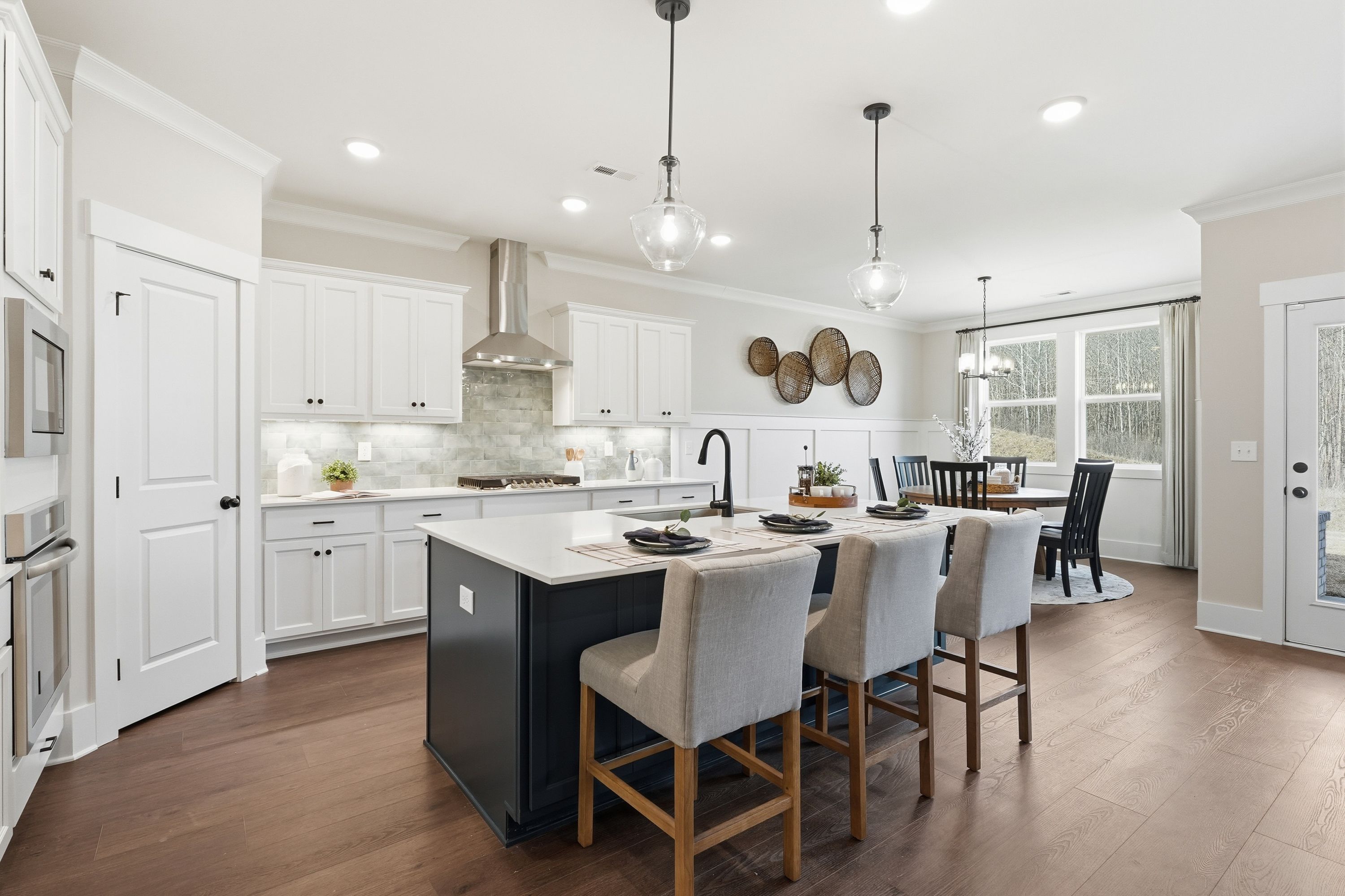 Spacious open-concept kitchen in Noble Ridge home, Cullman AL with white shaker cabinets, navy island, pendant lights, and hardwood floors