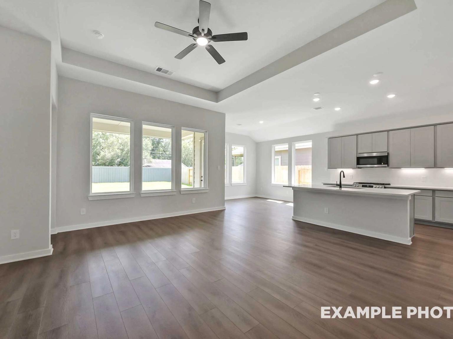 Open-concept living room and kitchen with tray ceiling in The Sequoia C floor plan at Sundance Cove, Crosby, Texas.
