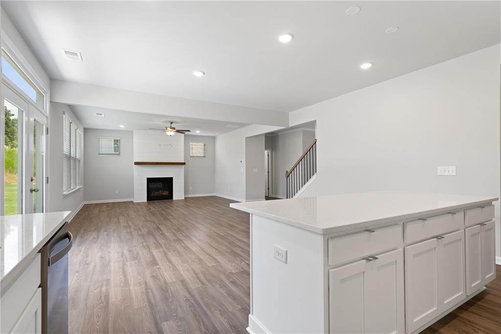 Spacious great room with gas fireplace, white kitchen island, hardwood floors, and large windows in Davidson Homes The Hickory A, Winder, Georgia