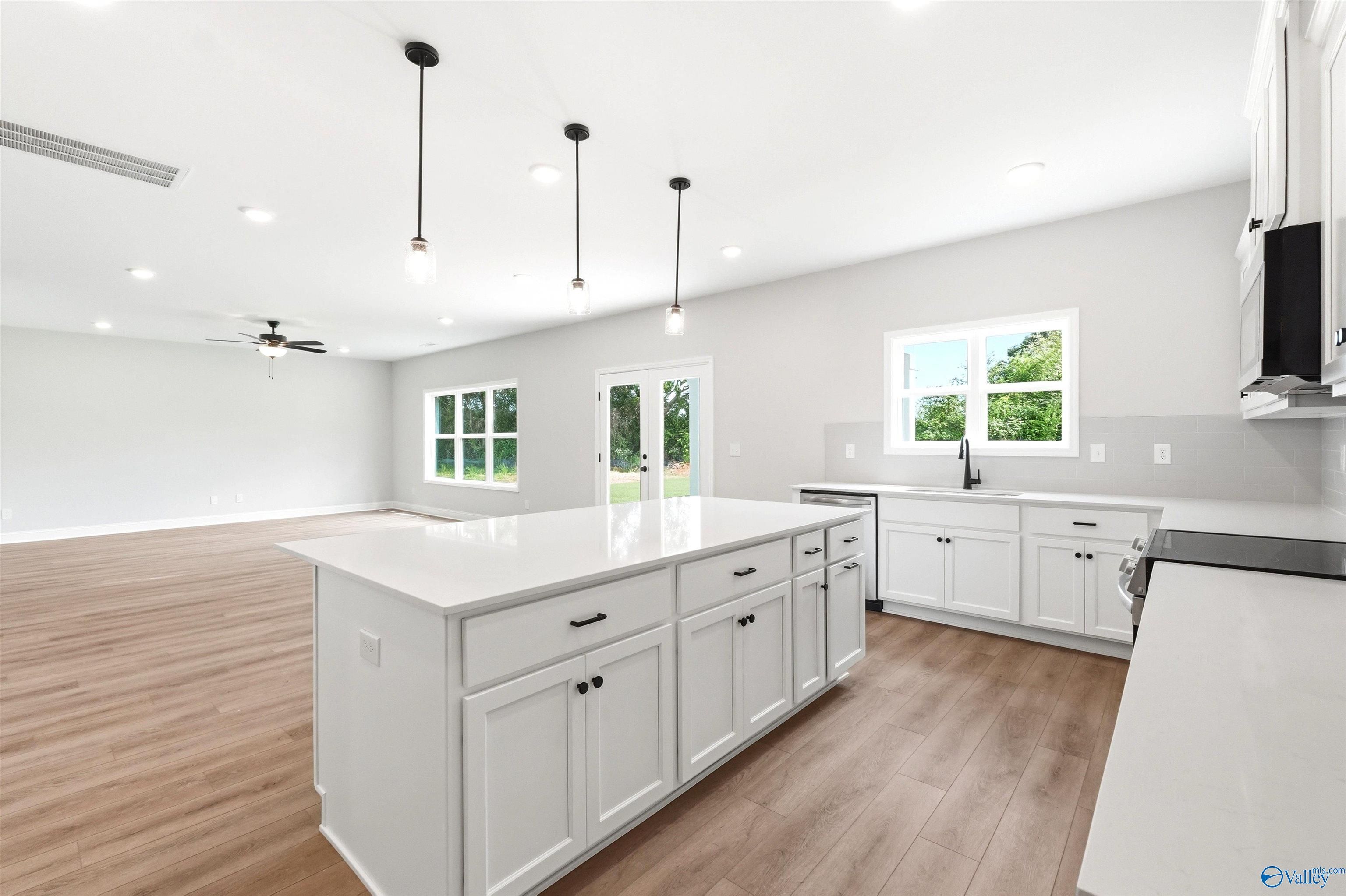 Open-concept kitchen with white cabinets and quartz island in The Chelsea D floor plan at Berry Cove, New Market, AL.