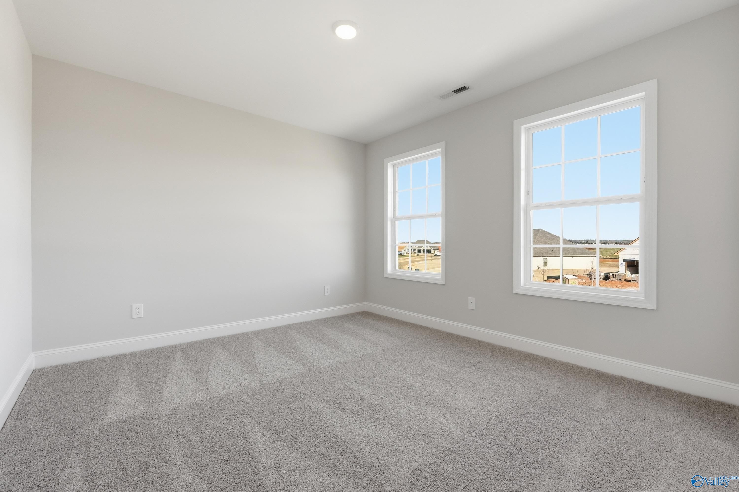 Bright bedroom with gray carpet, light walls, and sunny windows in Davidson Homes The Chelsea C, Harvest, Alabama