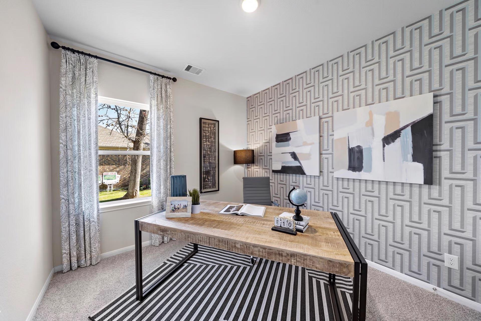 Modern home office at Saddle Creek Ranch in Cibolo Texas featuring geometric wallpaper, wooden desk, abstract art, and window view