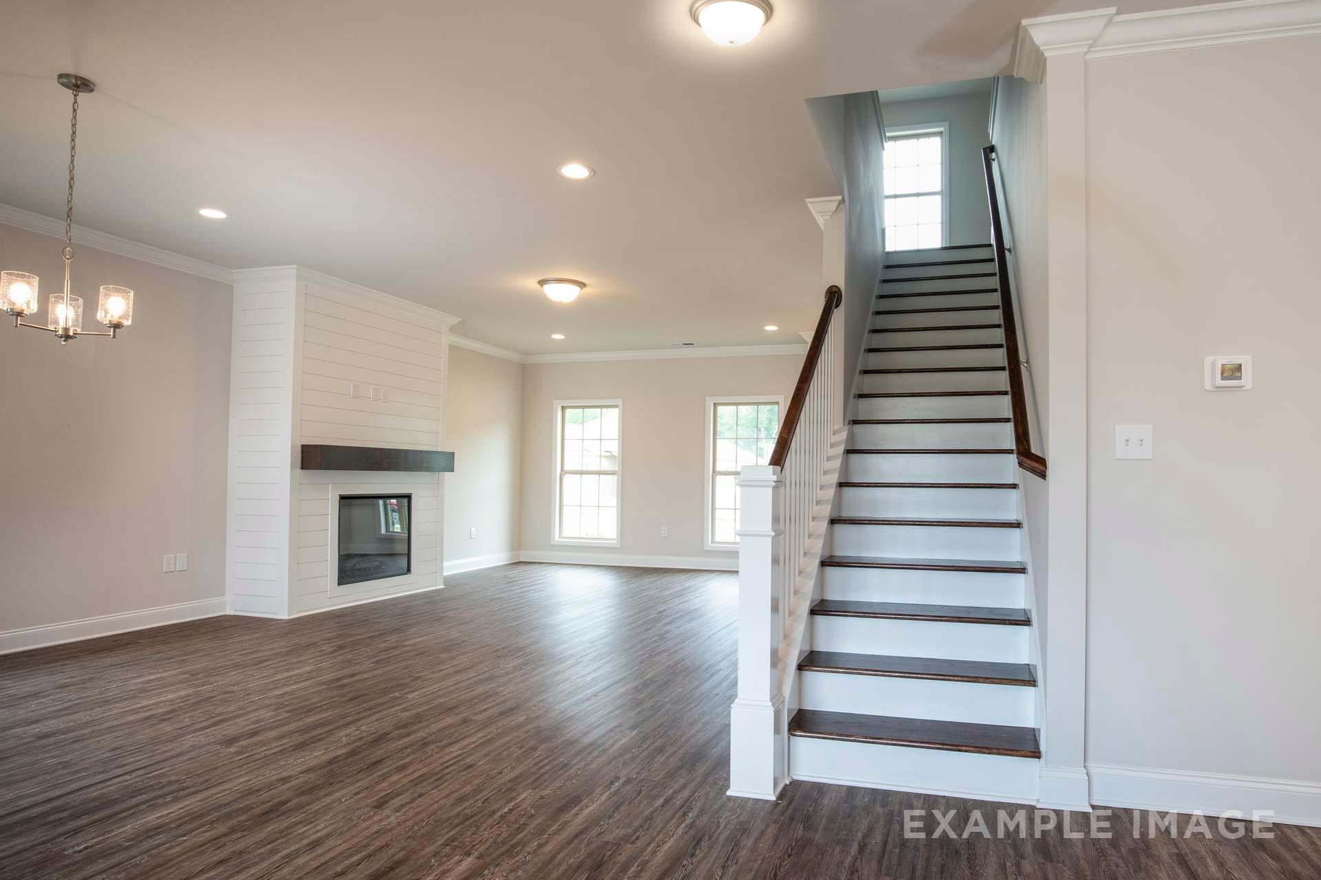 Open-concept living room in The Charleston 2-story home featuring modern fireplace, hardwood floors, and curved staircase
