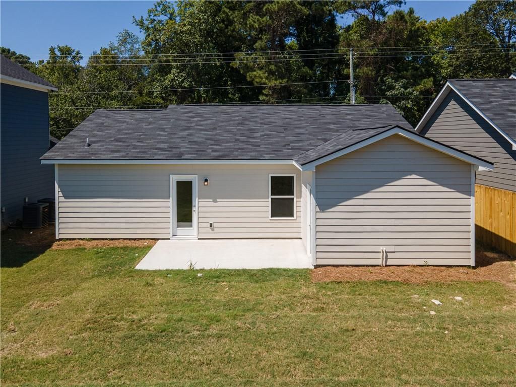Rear view of Davidson Homes The Washington single-story home with covered concrete patio, sliding glass door, and lush grassy yard in Summer Vineyard, Phenix City, Alabama