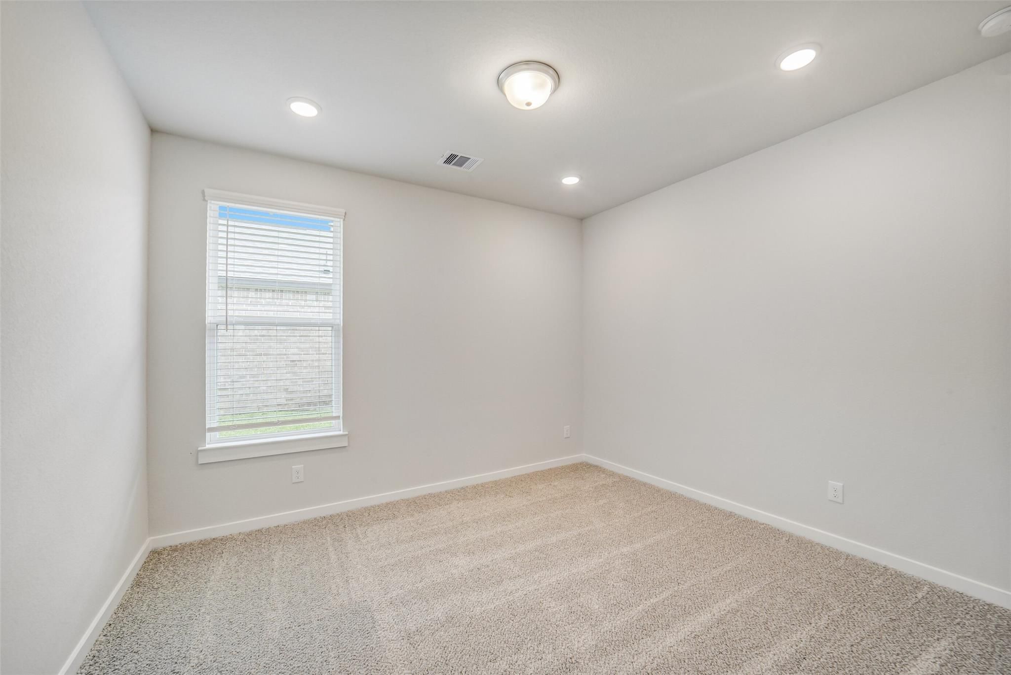 Empty bedroom with beige carpet, white walls, recessed lights, and window blinds in Davidson Homes The Acadia C, Magnolia TX