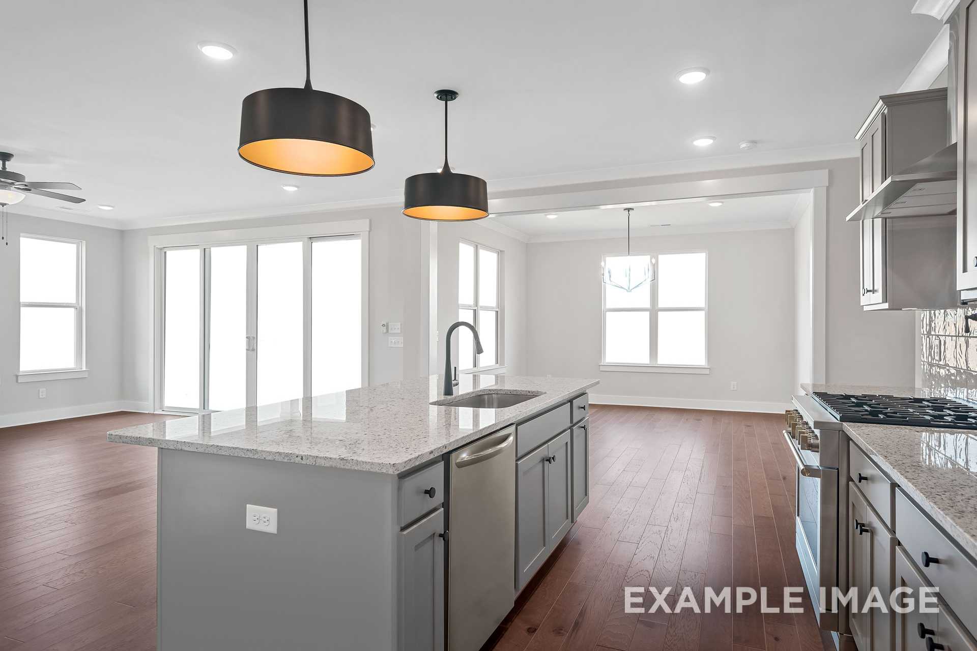 Spacious open-concept kitchen in The Hathaway home featuring gray shaker cabinets, large granite island, and pendant lights