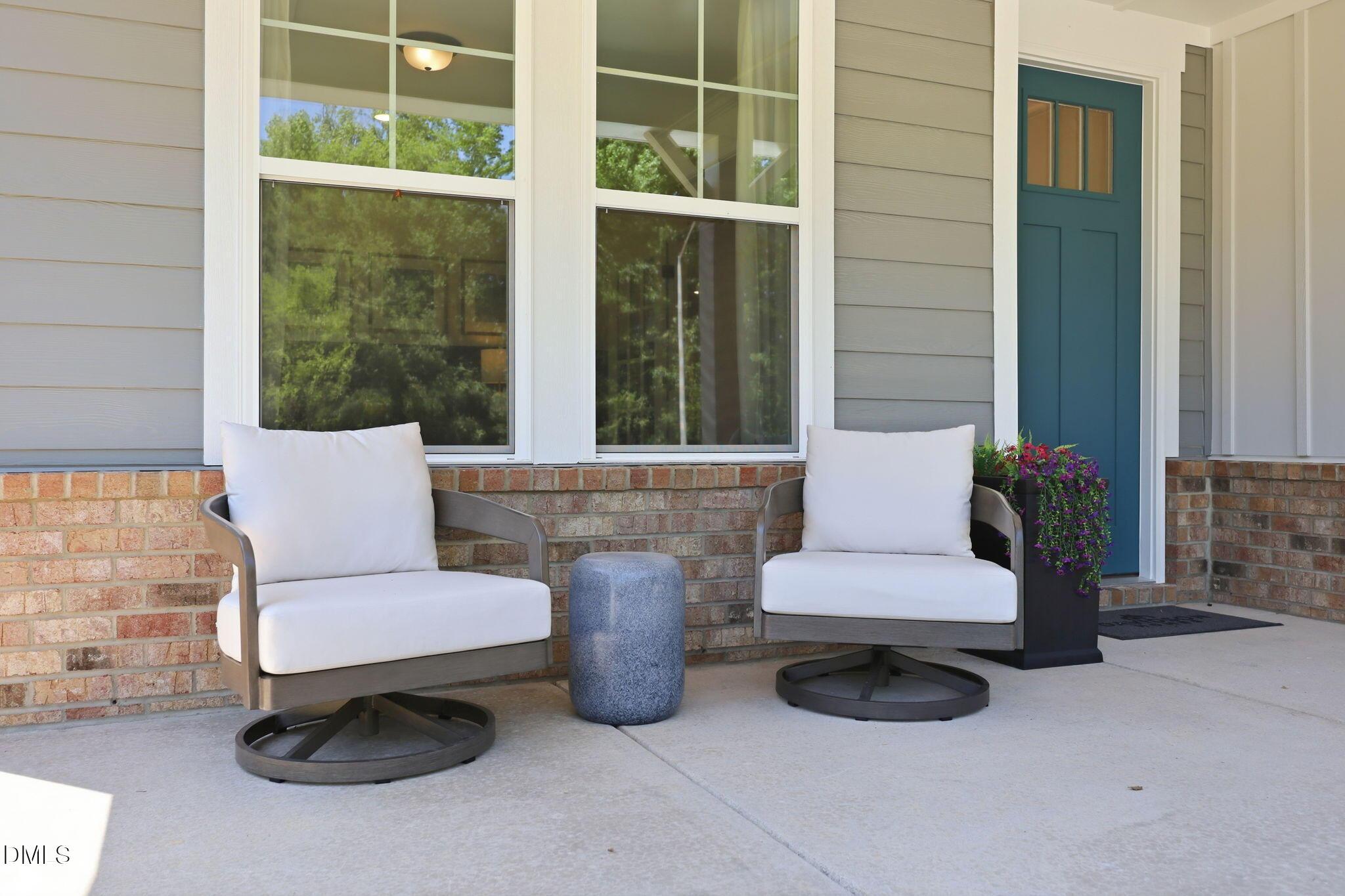 Covered front porch with two outdoor chairs and blue door at The Aspen B home in Wendell Ridge, Wendell, North Carolina.