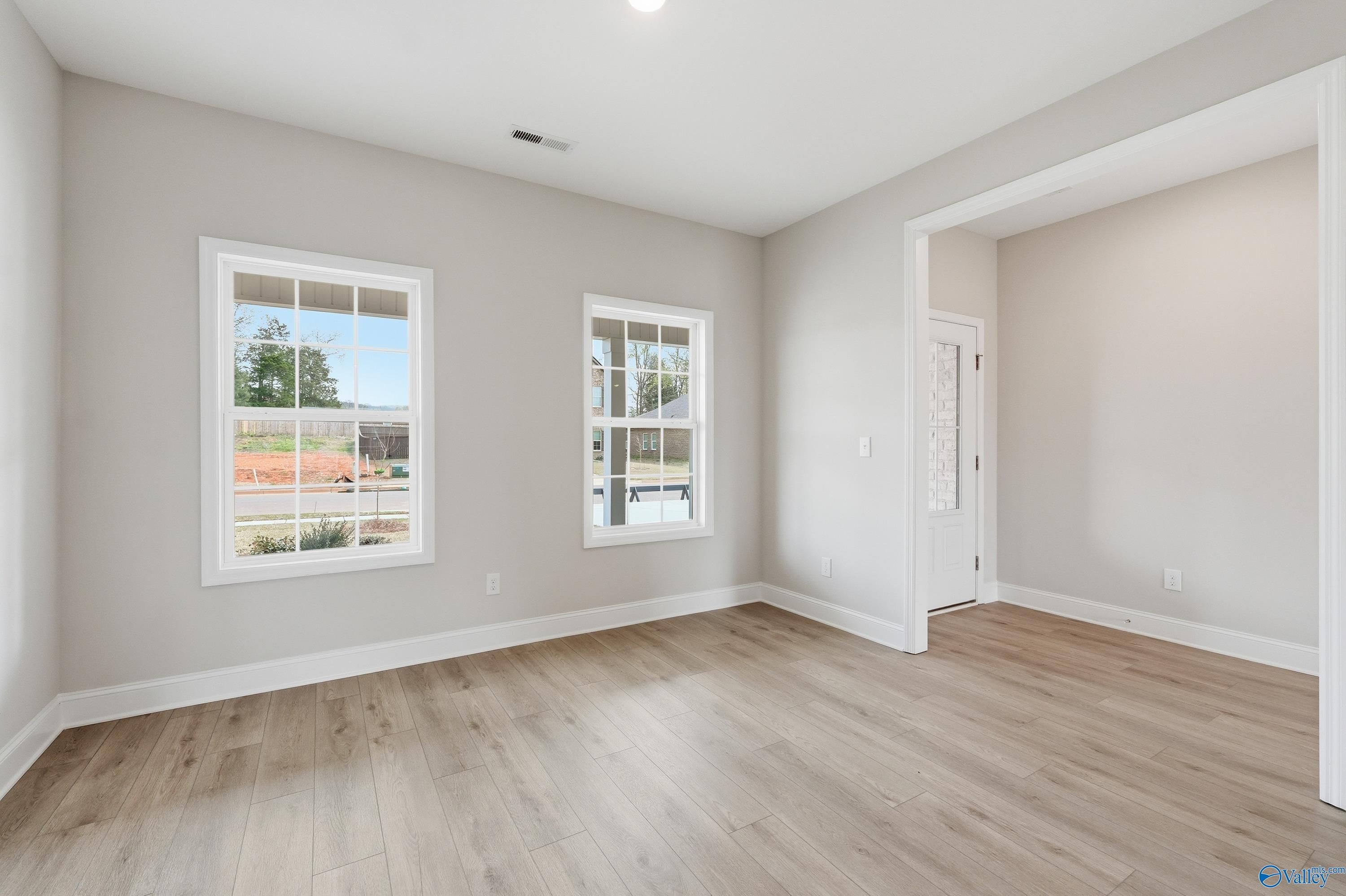 Bright empty living room with large windows, neutral walls, and hardwood floors in Davidson Homes Shelby B, New Market AL