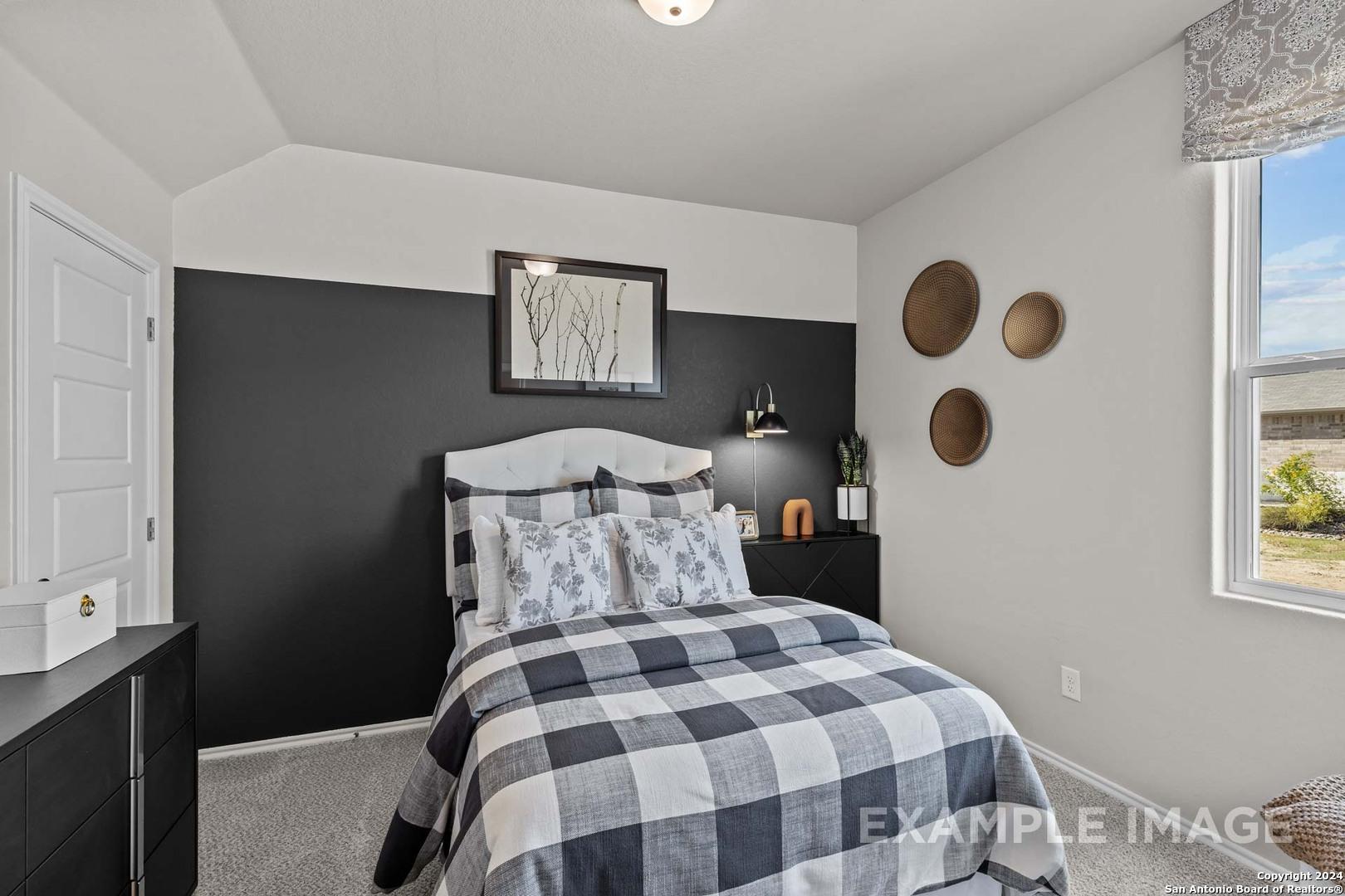 Cozy bedroom with black accent wall, checkered bedding, and window view in Davidson Homes The Sabine B, Applewhite Meadows, San Antonio