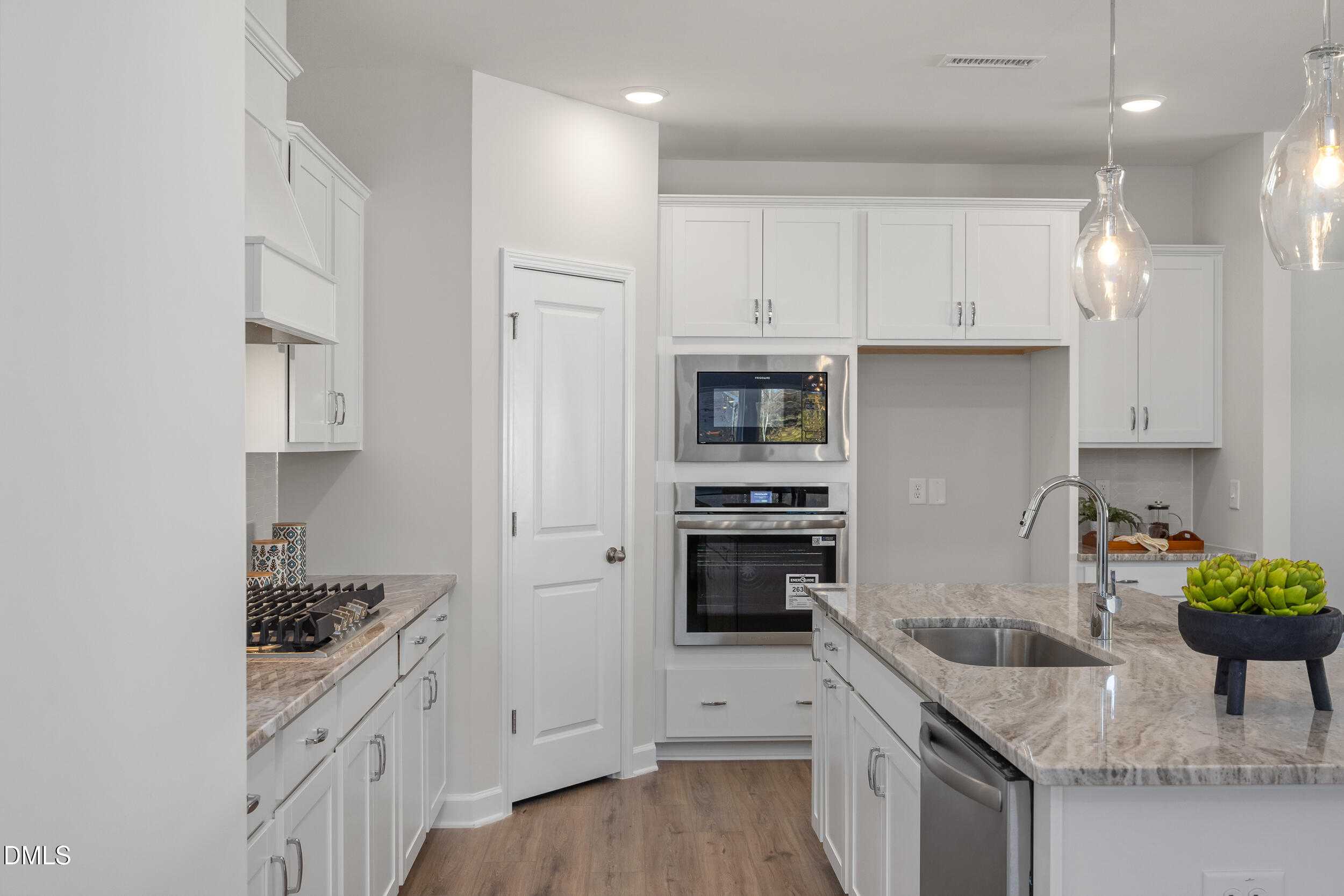 Modern white kitchen with granite countertops, stainless appliances, and island in The Preston C by Davidson Homes, Lillington, NC