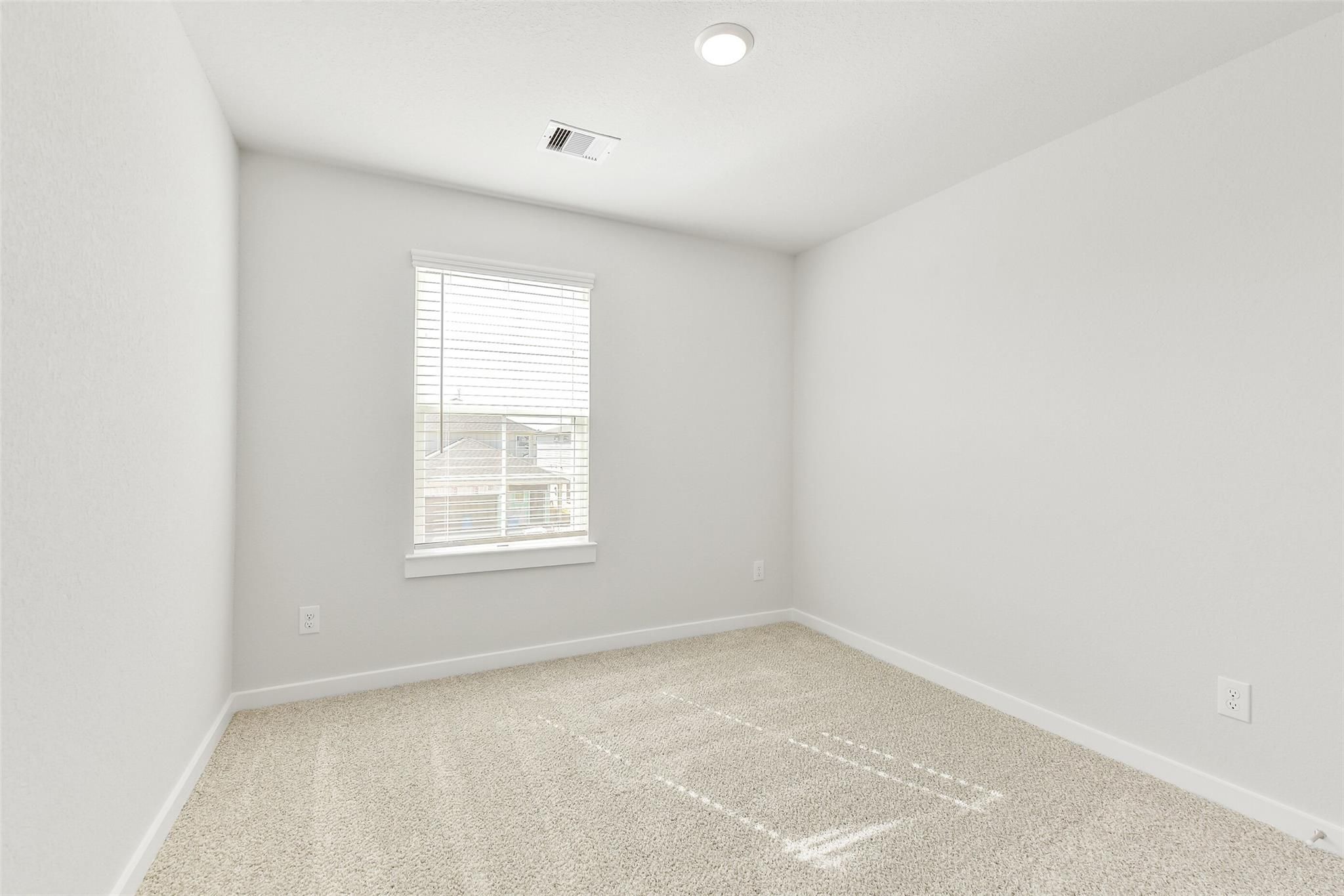 Bright secondary bedroom with neutral gray walls, beige carpet, and window blinds in Davidson Homes The Blanco E, Magnolia Texas
