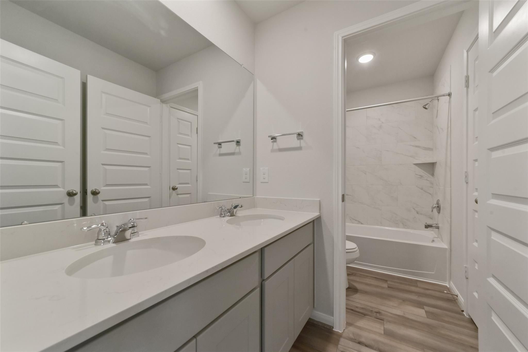 Modern bathroom with double vanity, bathtub, and tiled shower in 5-bedroom Davidson Homes San Marcos E, Beasley, Texas