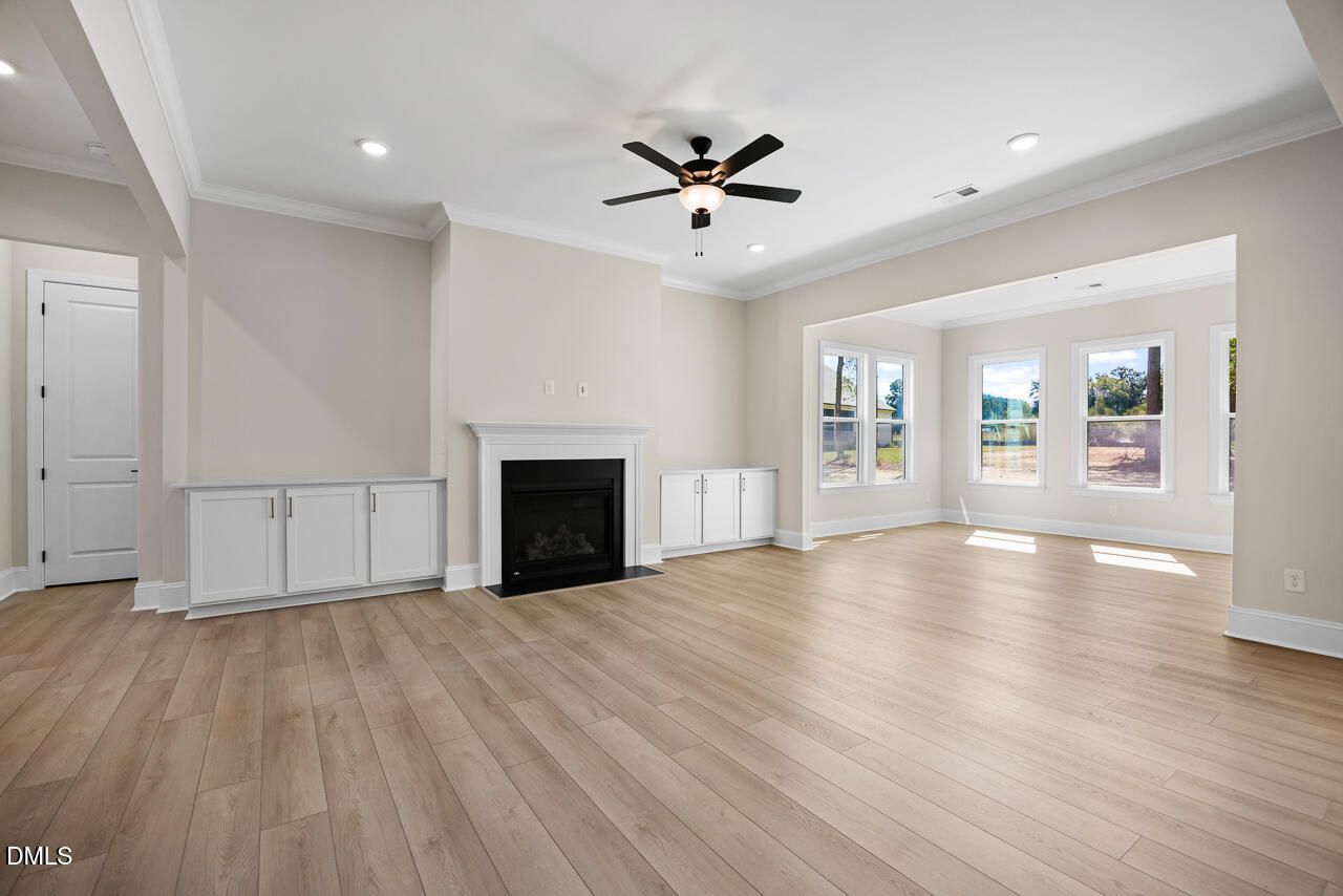 Bright family room with fireplace, built-in cabinets, ceiling fan, and hardwood floors in Davidson Homes The Crawford D, Wake Forest, NC