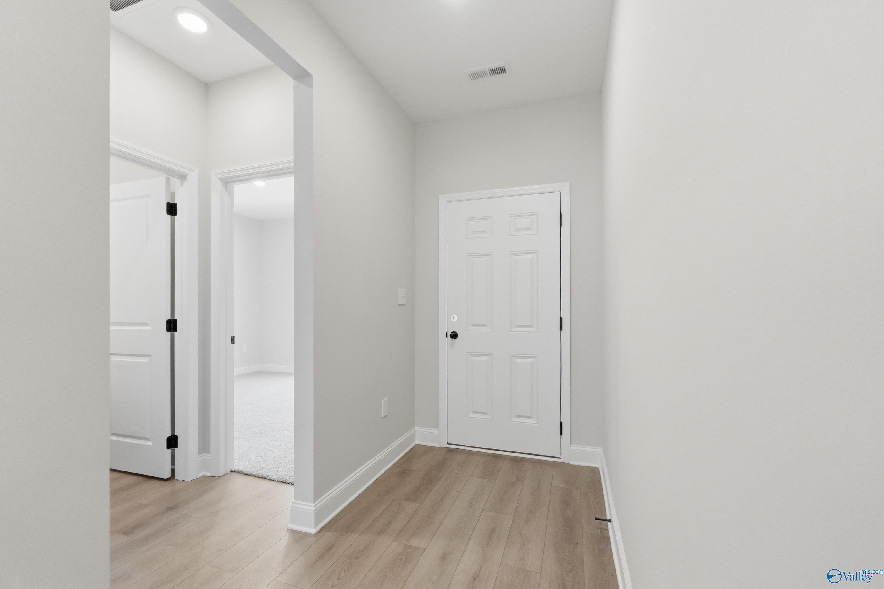 Bright hallway with open white doors, light wood floors, and recessed lighting in Davidson Homes The Franklin, Huntsville