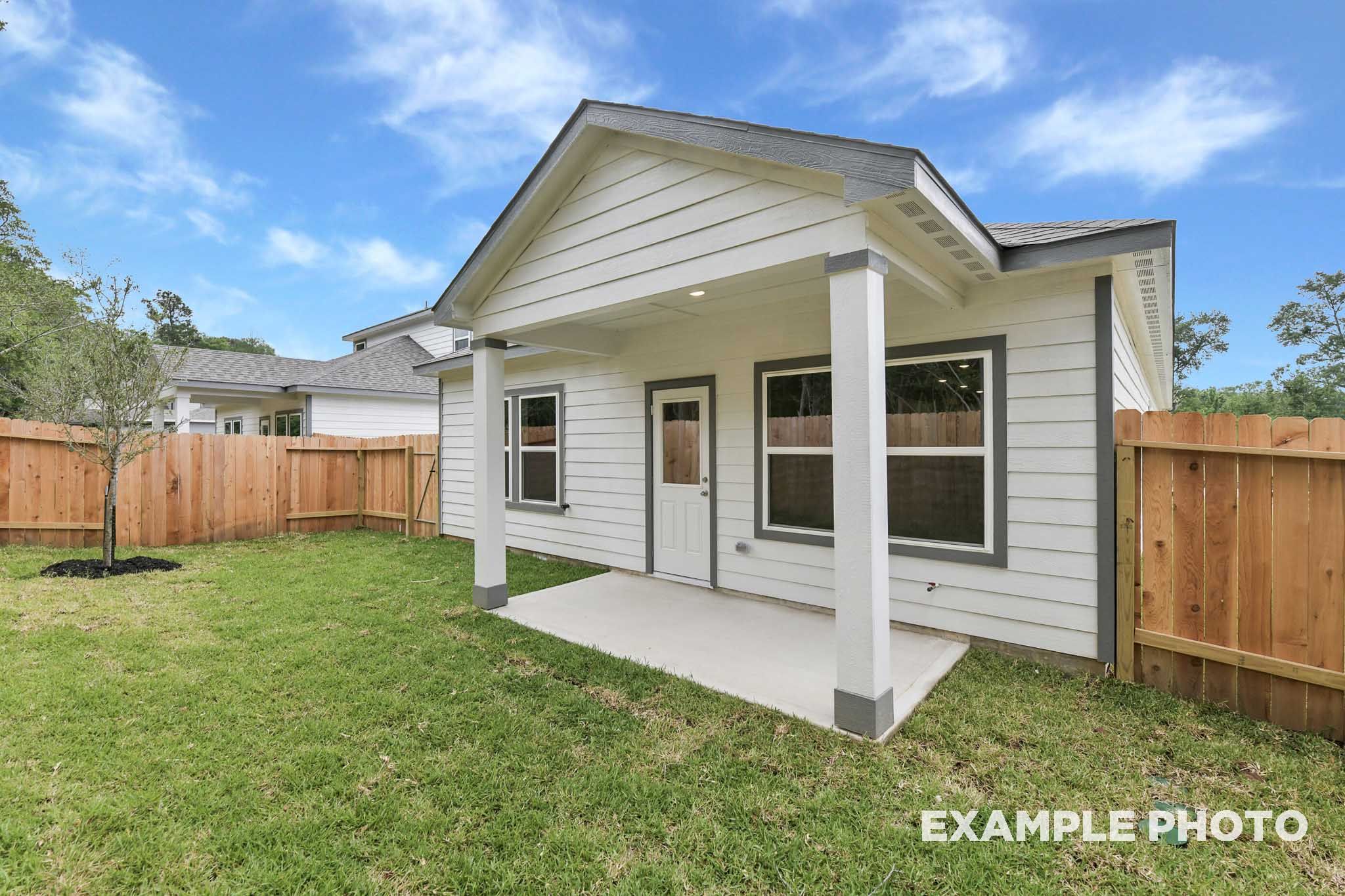 Covered back patio of The Frio floor plan by Davidson Homes featuring a spacious backyard and wood privacy fencing.