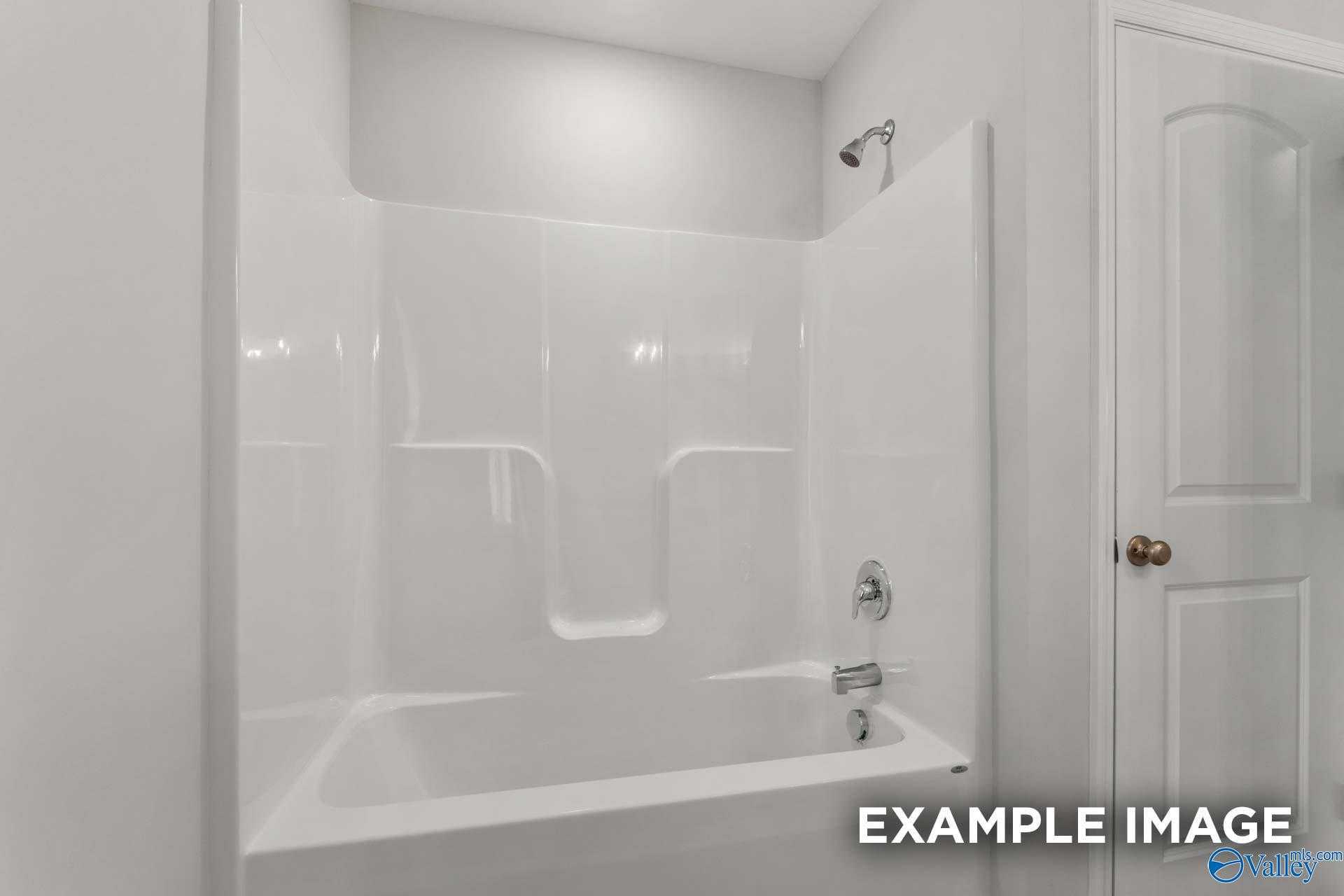 White bathtub with glass shower door and modern fixtures in The Shelby C bathroom, Davidson Homes, Meridianville, Alabama