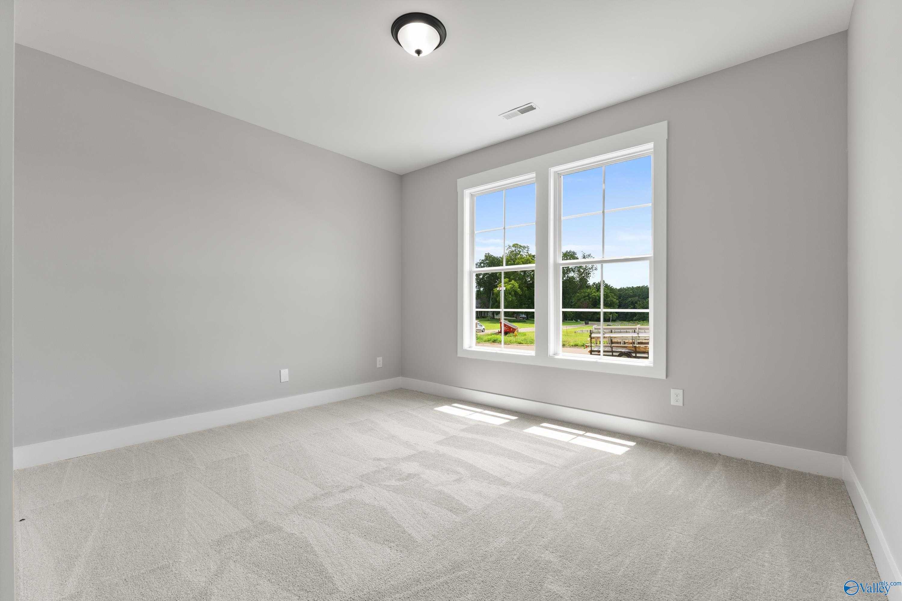 Bright secondary bedroom with light gray walls, plush carpet, and sunny double windows in Davidson Homes The Arcadia, Huntsville
