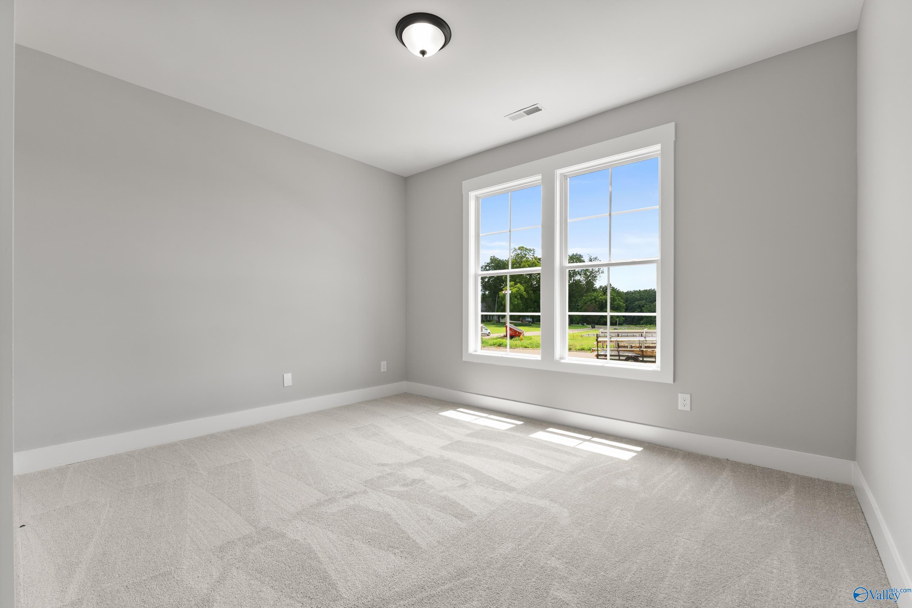 Bright secondary bedroom with light gray walls, plush carpet, and sunny double windows in Davidson Homes The Arcadia, Huntsville