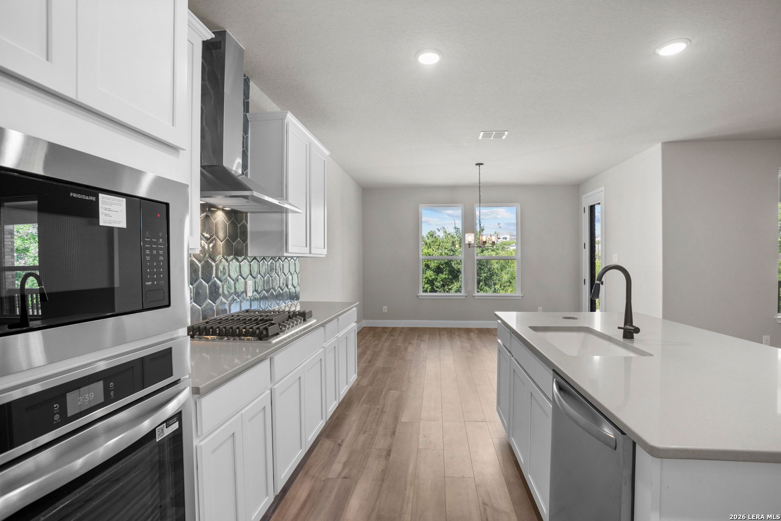 Modern kitchen with white cabinets, quartz island, and tile backsplash in The Jennings G plan at Ladera, San Antonio.