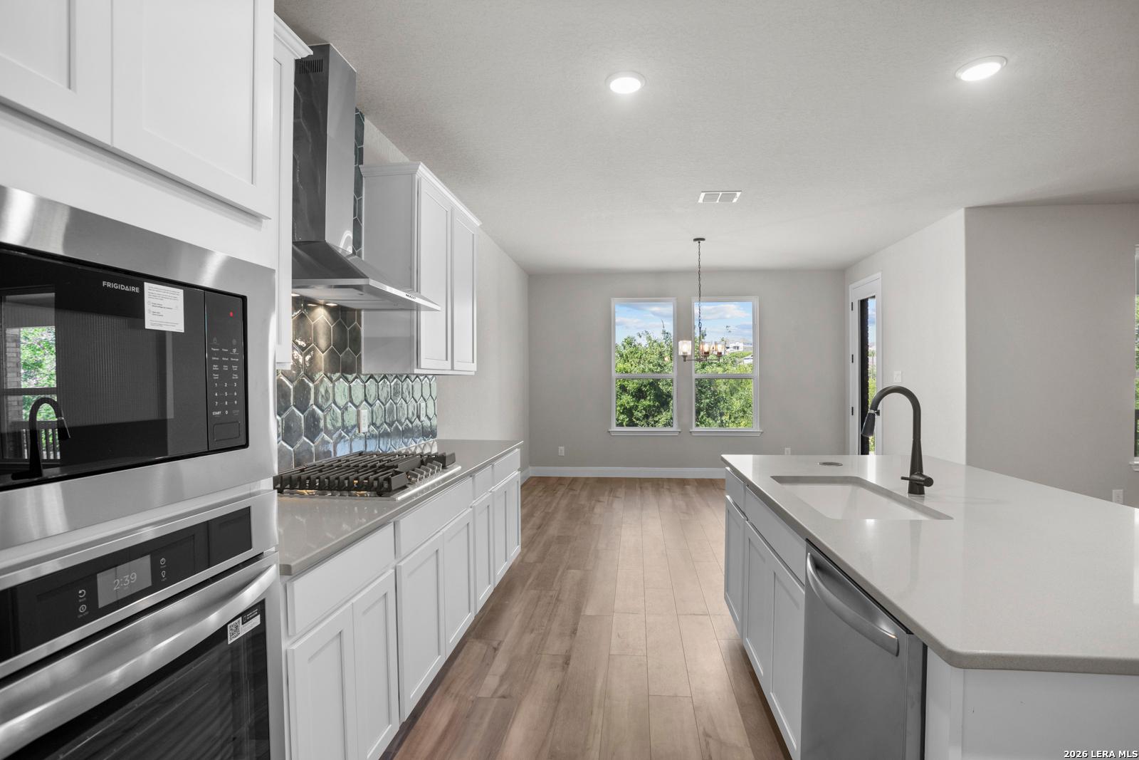 Modern kitchen with white cabinets, quartz island, and tile backsplash in The Jennings G plan at Ladera, San Antonio.