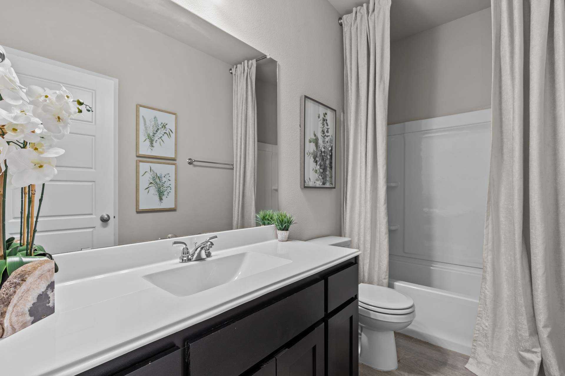 Spacious master bathroom in The Collin B with double vanity, soaking tub, neutral tones, and potted orchids
