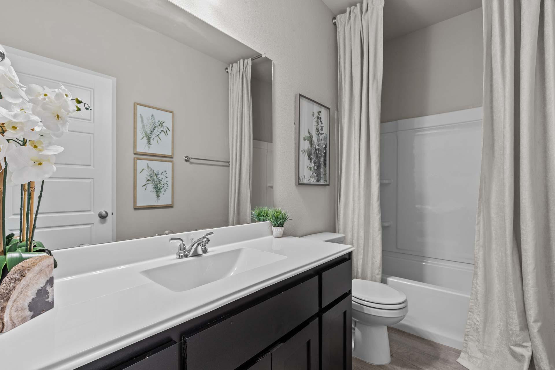 Spacious master bathroom in The Collin A with double vanity, soaking tub, orchids, and botanical wall art