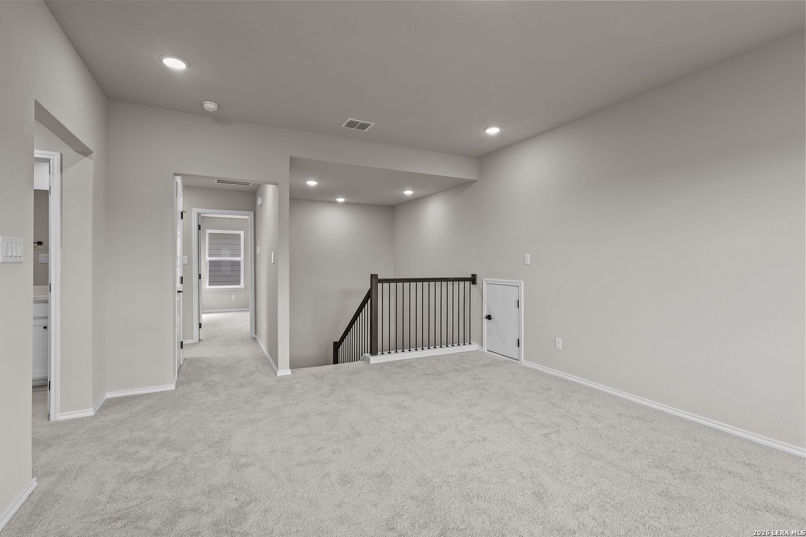 Spacious carpeted upstairs loft with wrought iron stair railing in Davidson Homes The Sequoia C, Royal Crest, San Antonio, Texas