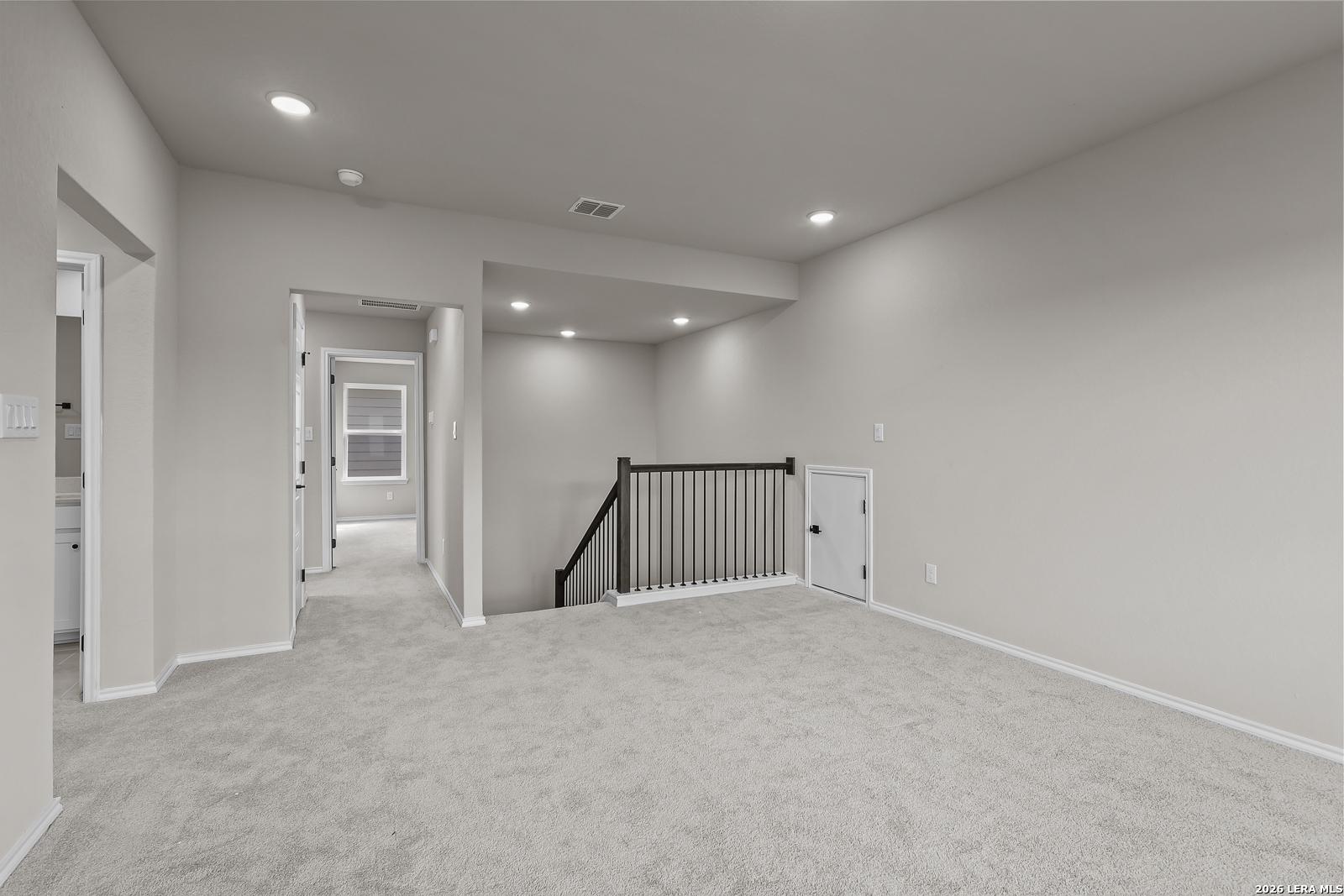 Spacious carpeted upstairs loft with wrought iron stair railing in Davidson Homes The Sequoia C, Royal Crest, San Antonio, Texas