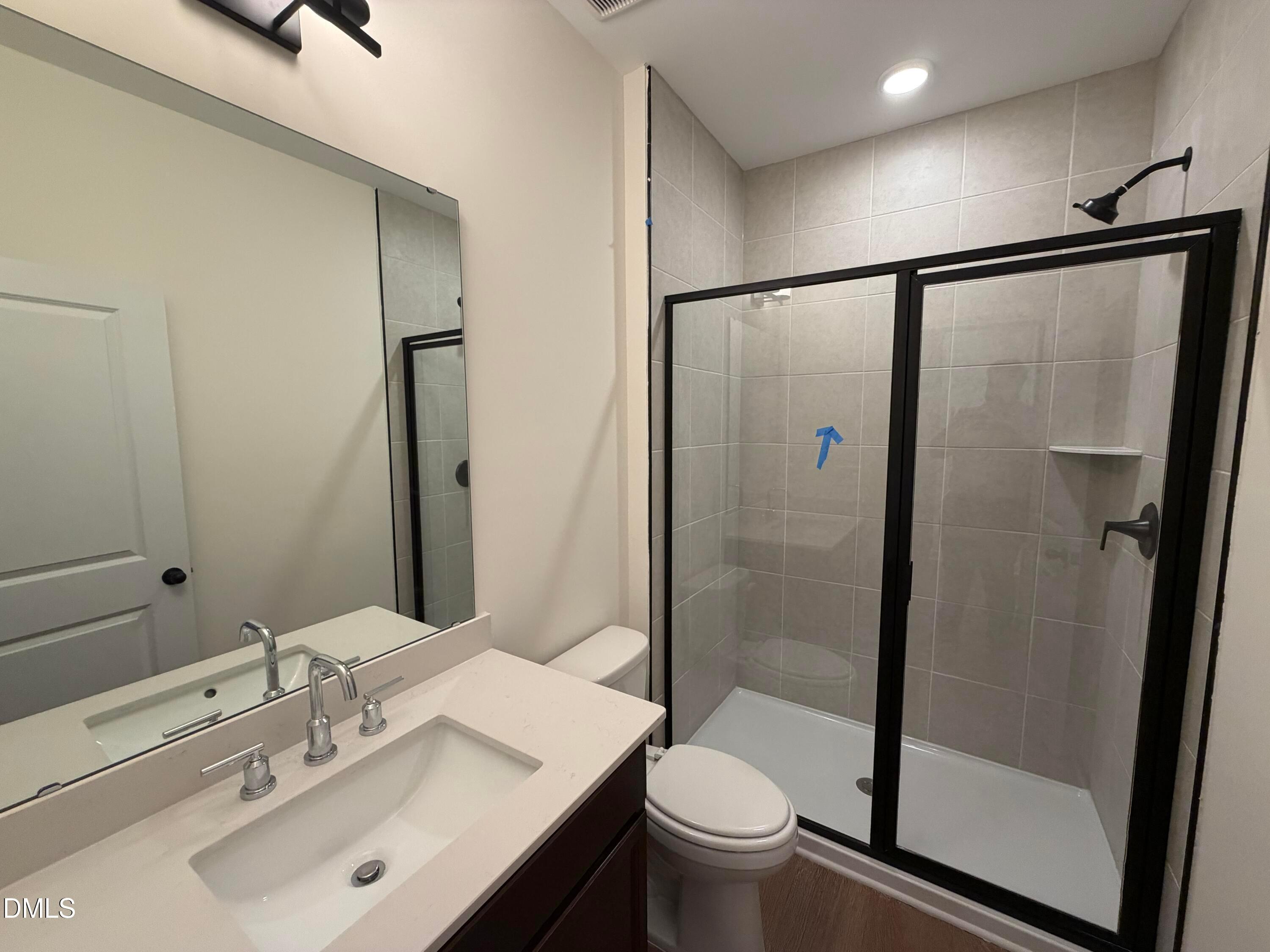 Modern bathroom with quartz vanity, framed mirror, and black-finished glass shower in Davidson Homes The Ashport M, Wendell Ridge, NC
