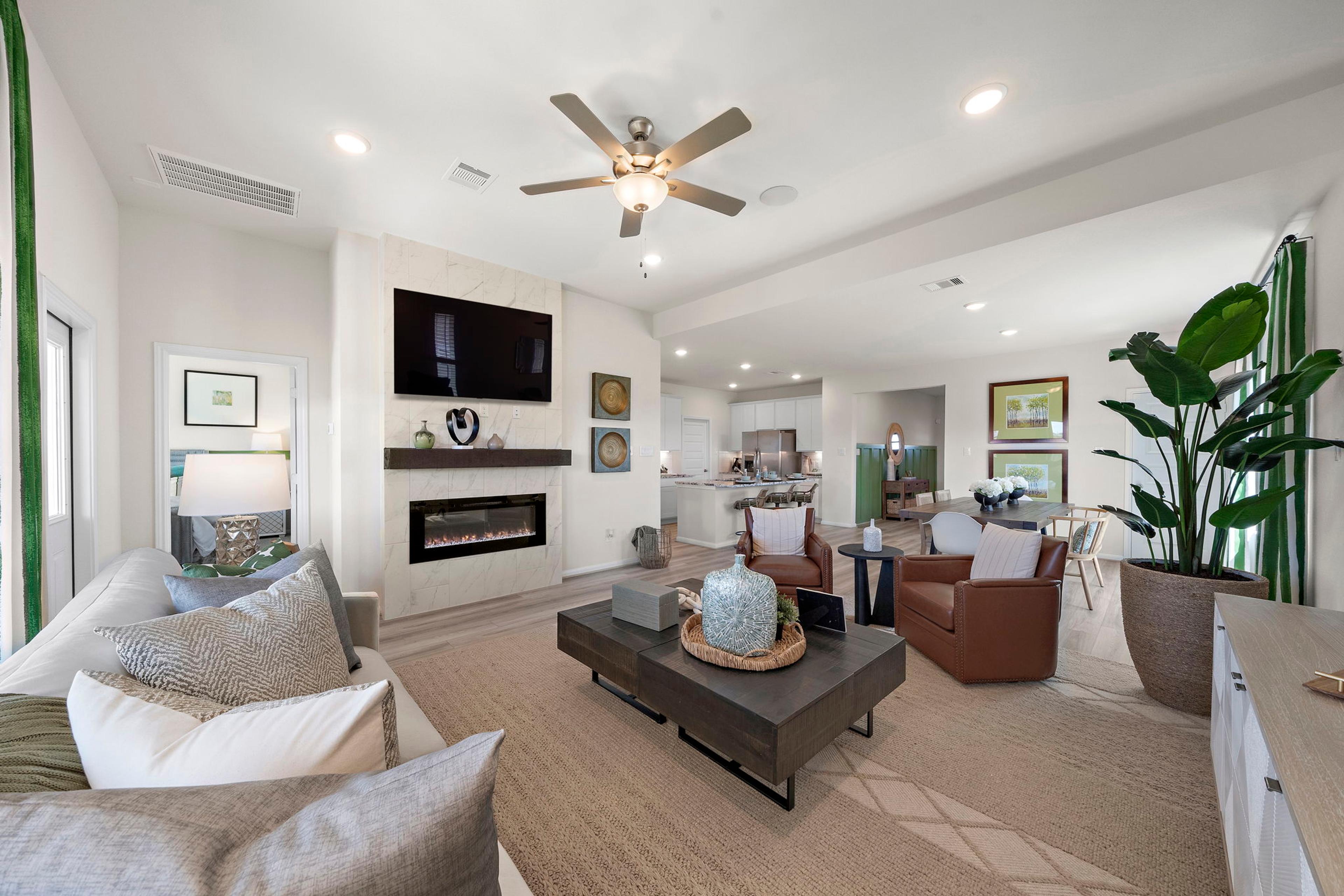 Spacious open-concept living room at River Ranch Meadows in Dayton Texas with modern gas fireplace, TV wall, cozy sofas and large potted plant