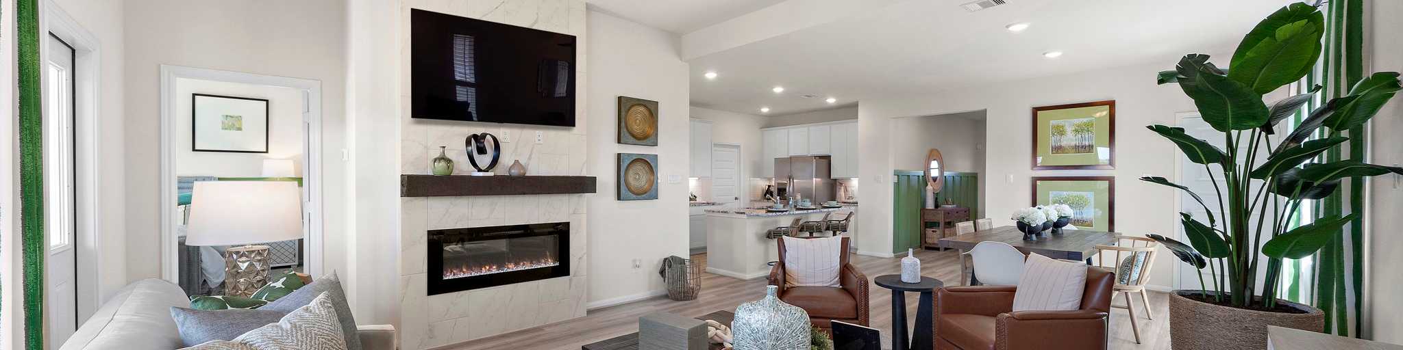 Spacious open-concept living room at River Ranch Meadows in Dayton Texas with modern gas fireplace, TV wall, cozy sofas and large potted plant