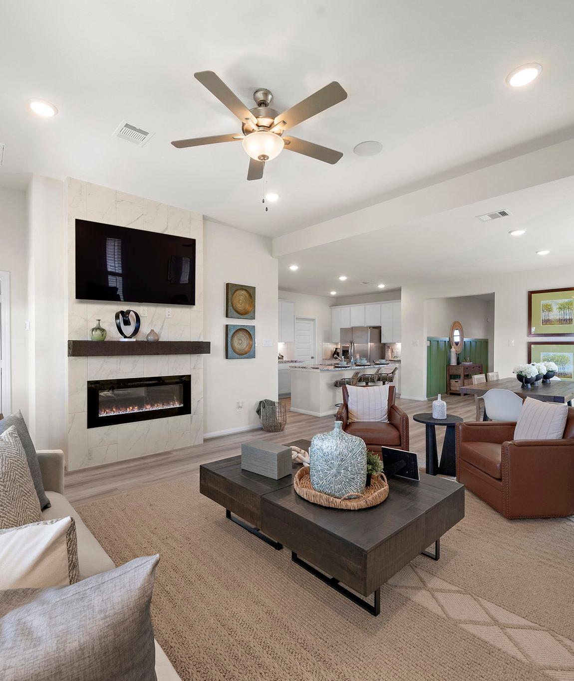 Spacious open-concept living room at River Ranch Meadows in Dayton Texas with modern gas fireplace, TV wall, cozy sofas and large potted plant