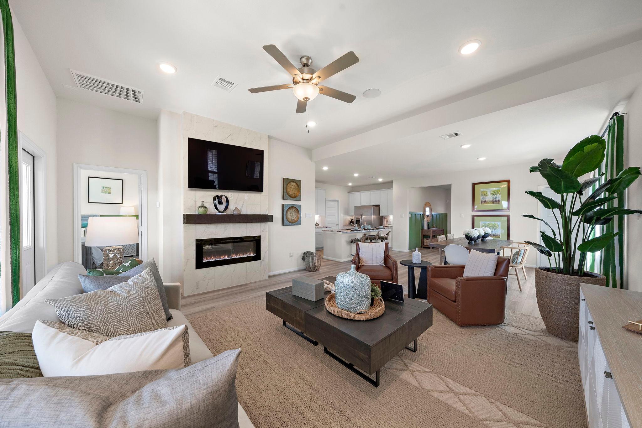 Spacious open-concept living room at River Ranch Meadows in Dayton Texas with modern gas fireplace, TV wall, cozy sofas and large potted plant