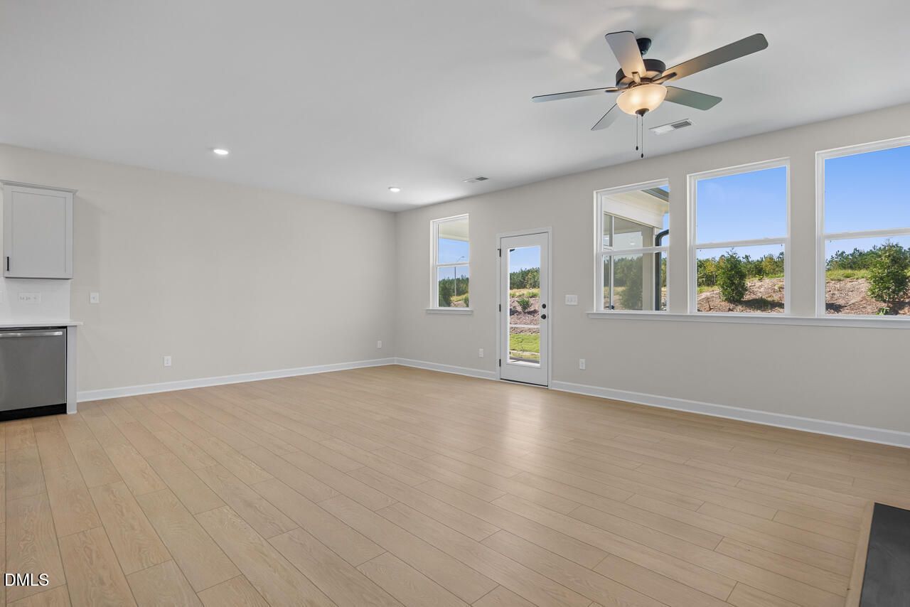 Bright open-concept living area with luxury vinyl plank floors, ceiling fan, and backyard views in Davidson Homes Ashport M plan.