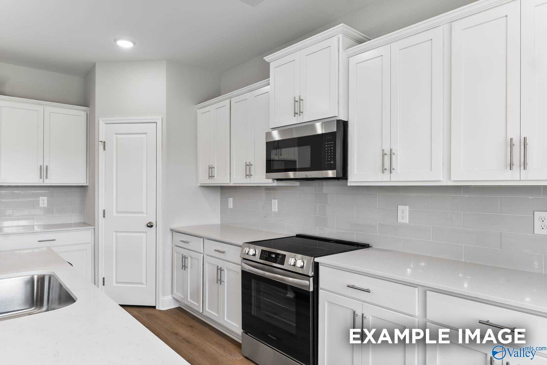 Modern white shaker kitchen with stainless steel appliances, subway tile backsplash, quartz counters in The Madison A, Davidson Homes, Harvest AL