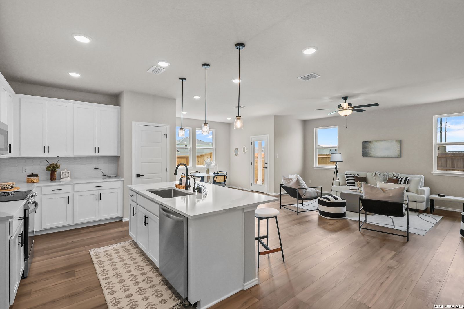Open-concept kitchen and living area with white cabinets and kitchen island in The Daphne H floor plan, Seguin, Texas.