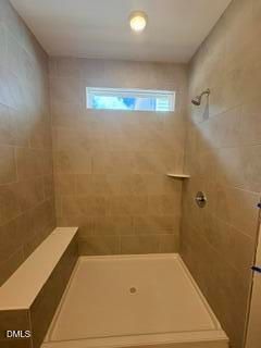 Walk-in tile shower with built-in bench in The Daphne D floor plan at Woodland Crossing in Zebulon, North Carolina.