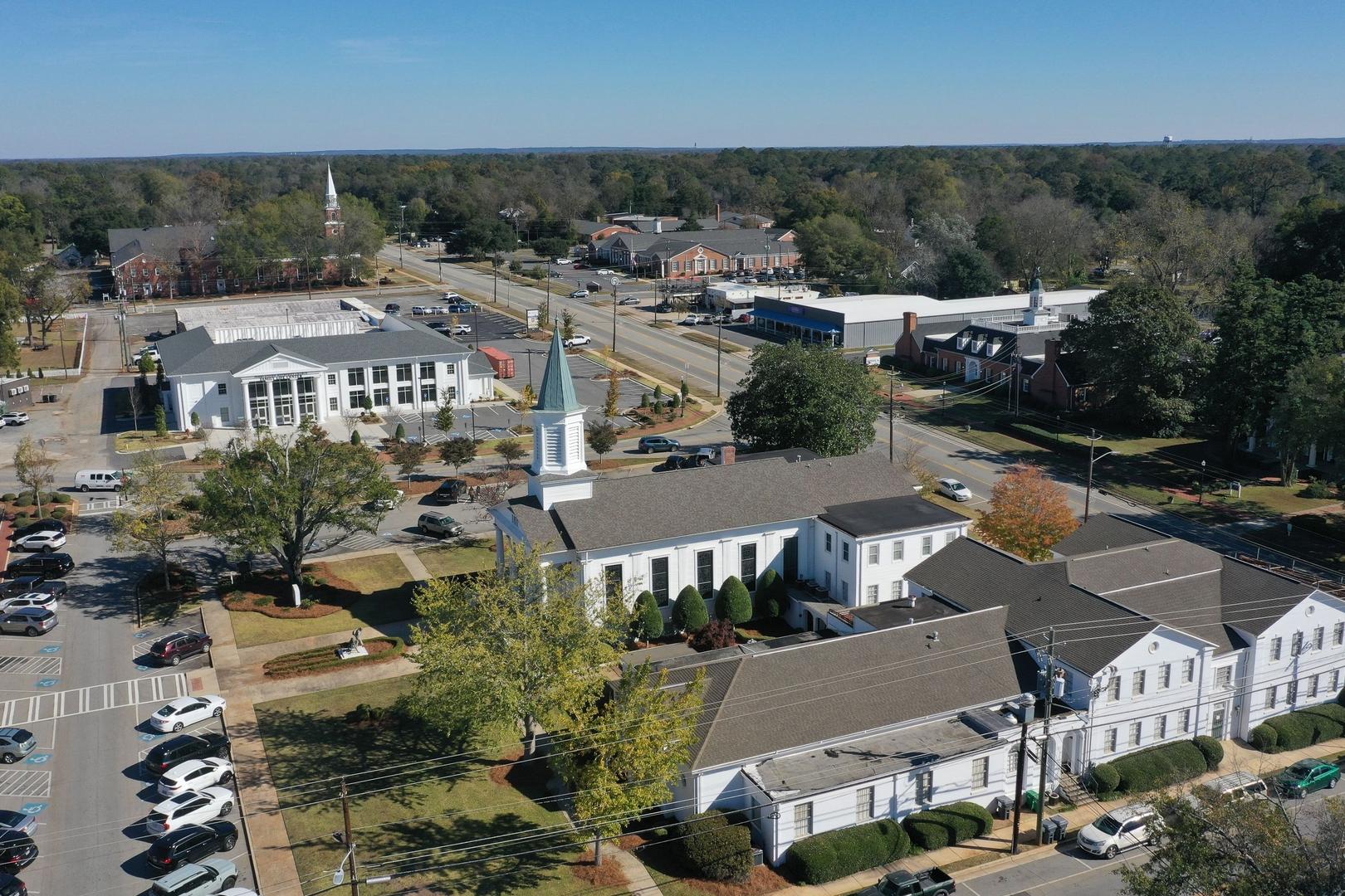 Aerial view of Ivy Glen neighborhood in Perry Georgia featuring white church with steeple tree-lined streets and residential buildings by Evermore Homes