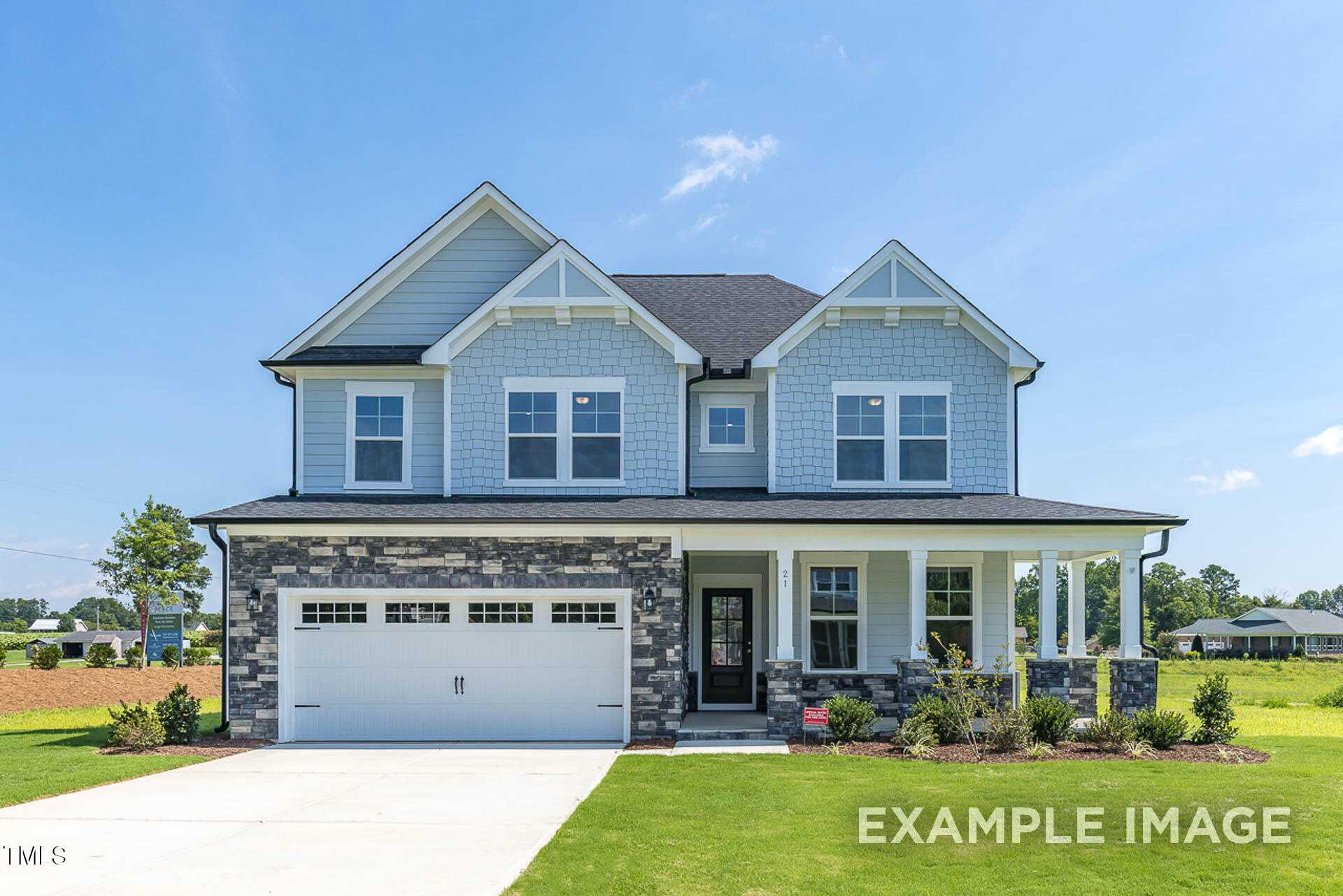 Two-story light blue Willow C home by Davidson Homes featuring 2-car garage, front porch, and lush lawn in Tobacco Road, Angier, NC
