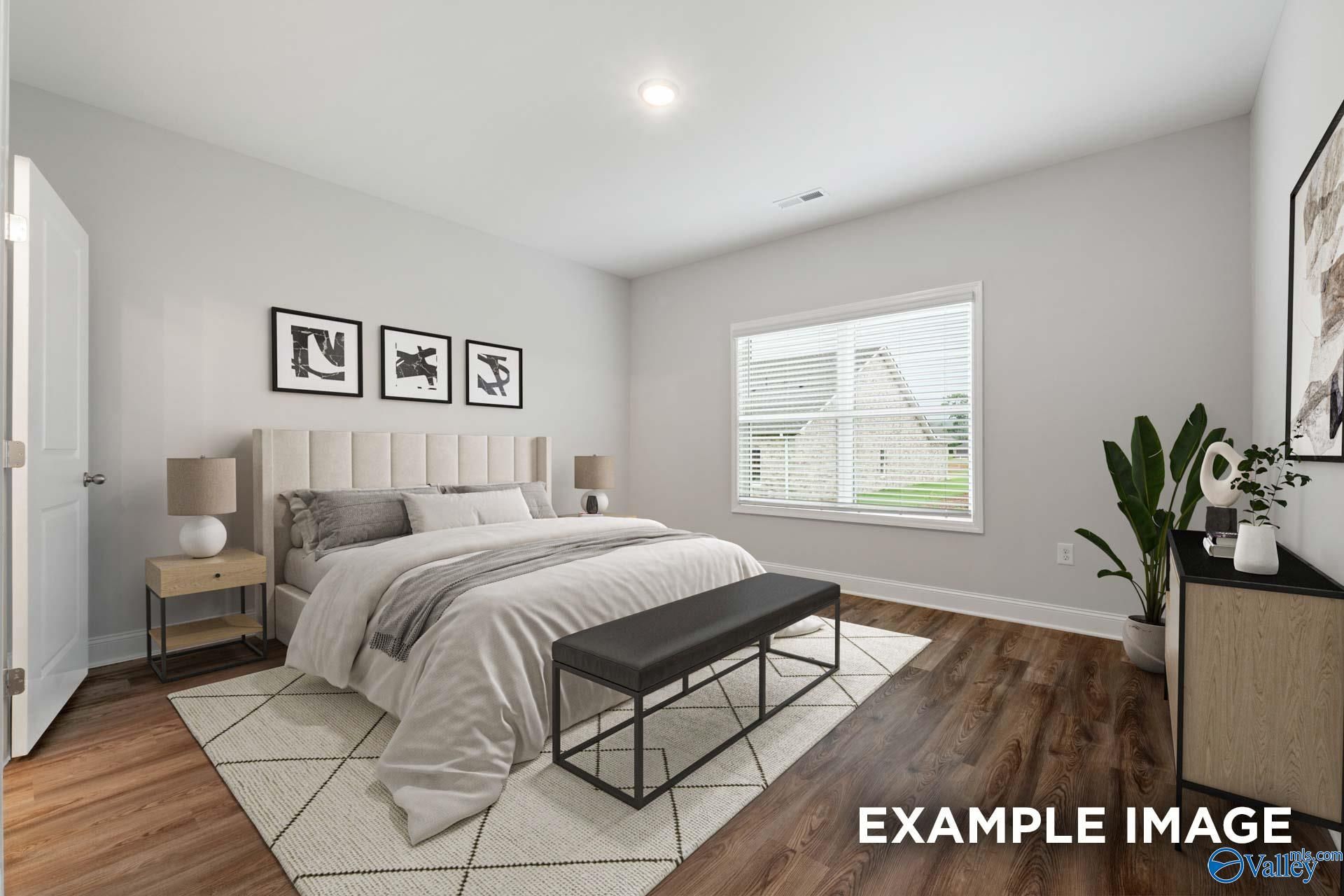 Cozy master bedroom with king bed, neutral gray walls, large window, and modern decor in Davidson Homes The Cumberland, Decatur, AL