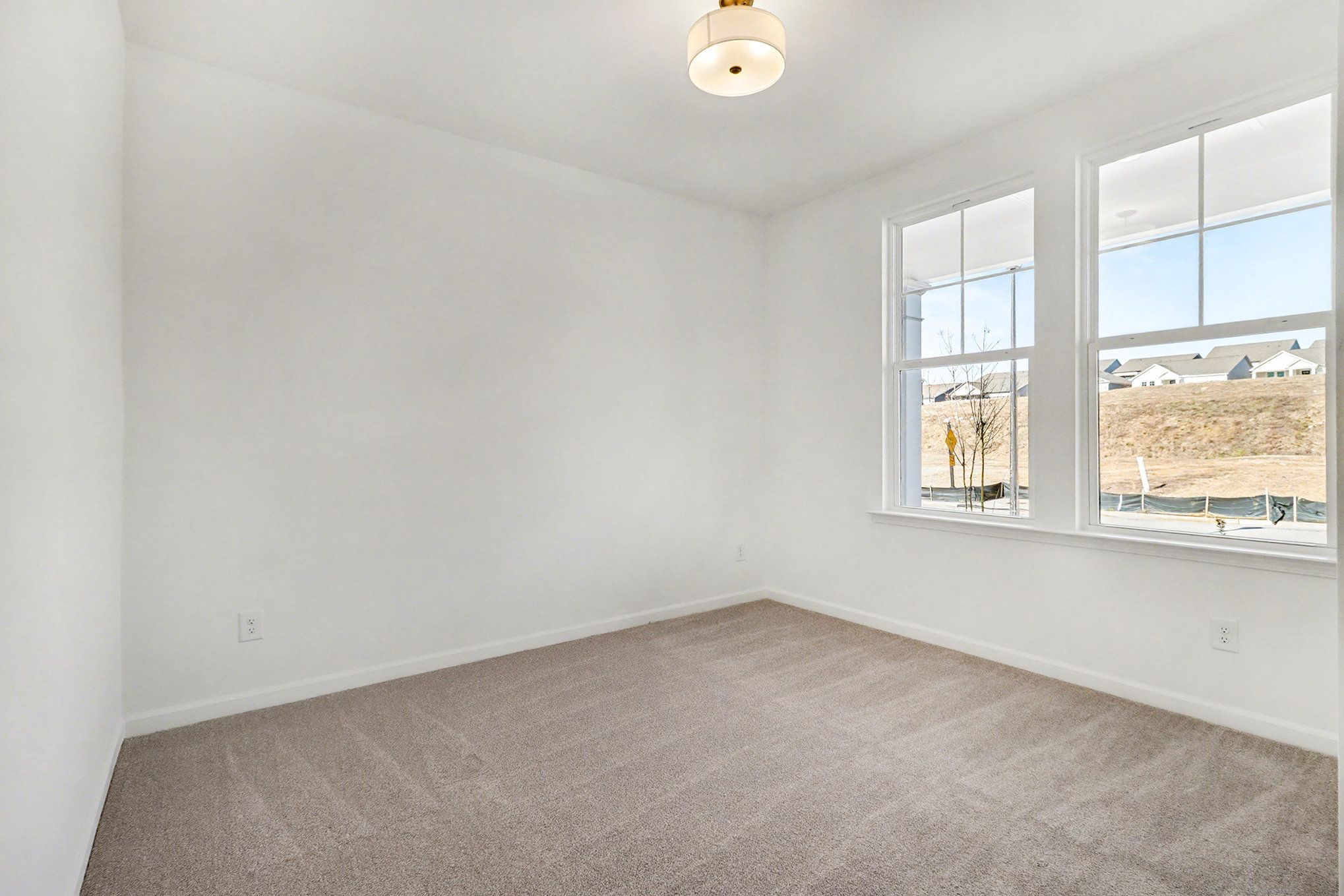 Bright bedroom with large windows overlooking wooded lot, white doors, beige walls, gray carpet in Davidson Homes The Daphne B, Loganville, GA