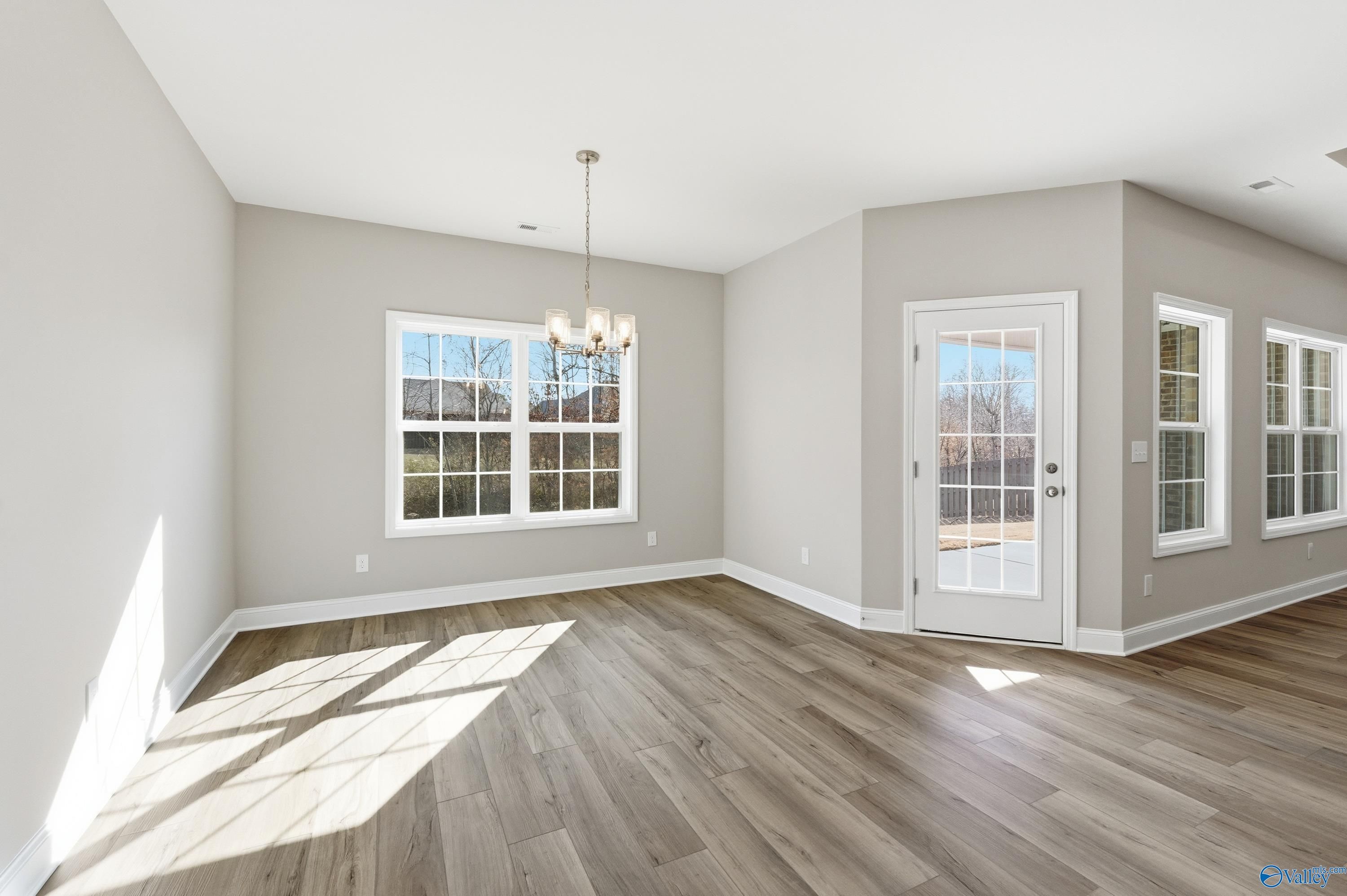 Bright dining room with hardwood floors, chandelier, French doors, and natural light in Davidson Homes The Rockford, Harvest, Alabama