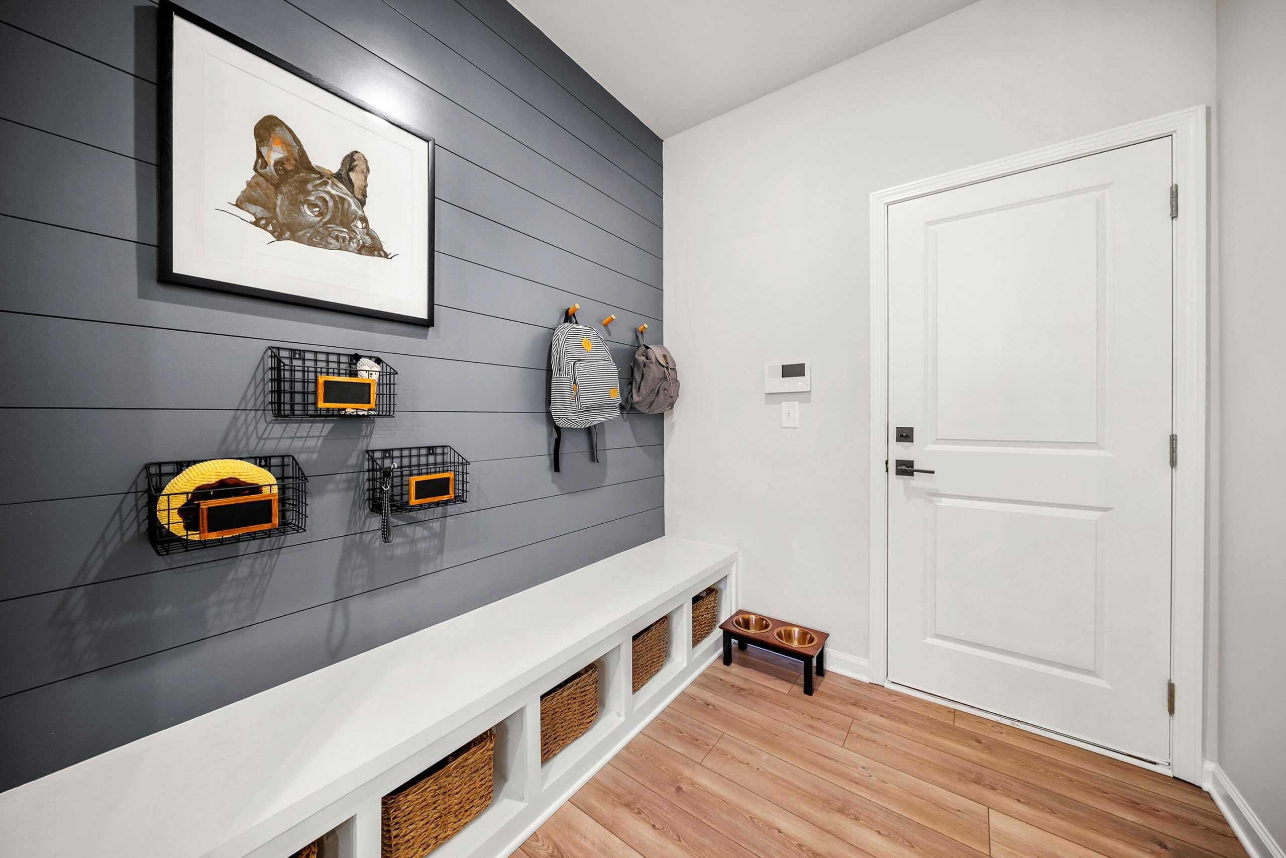 Functional mudroom in Riverwood Dallas Georgia with gray shiplap wall, built-in bench, backpack hooks, and woven storage baskets