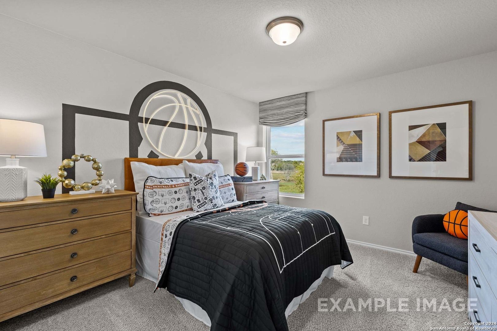 Basketball-themed bedroom with orange hoop headboard, black patterned bedding, and window view in Davidson Homes The Sabine B, San Antonio