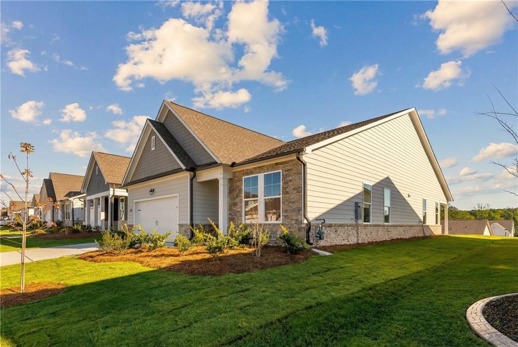 Modern single-story 3-bedroom home with 2-car garage, stone accents, and lush lawn in Kelly Preserve, Loganville, Georgia by Davidson Homes