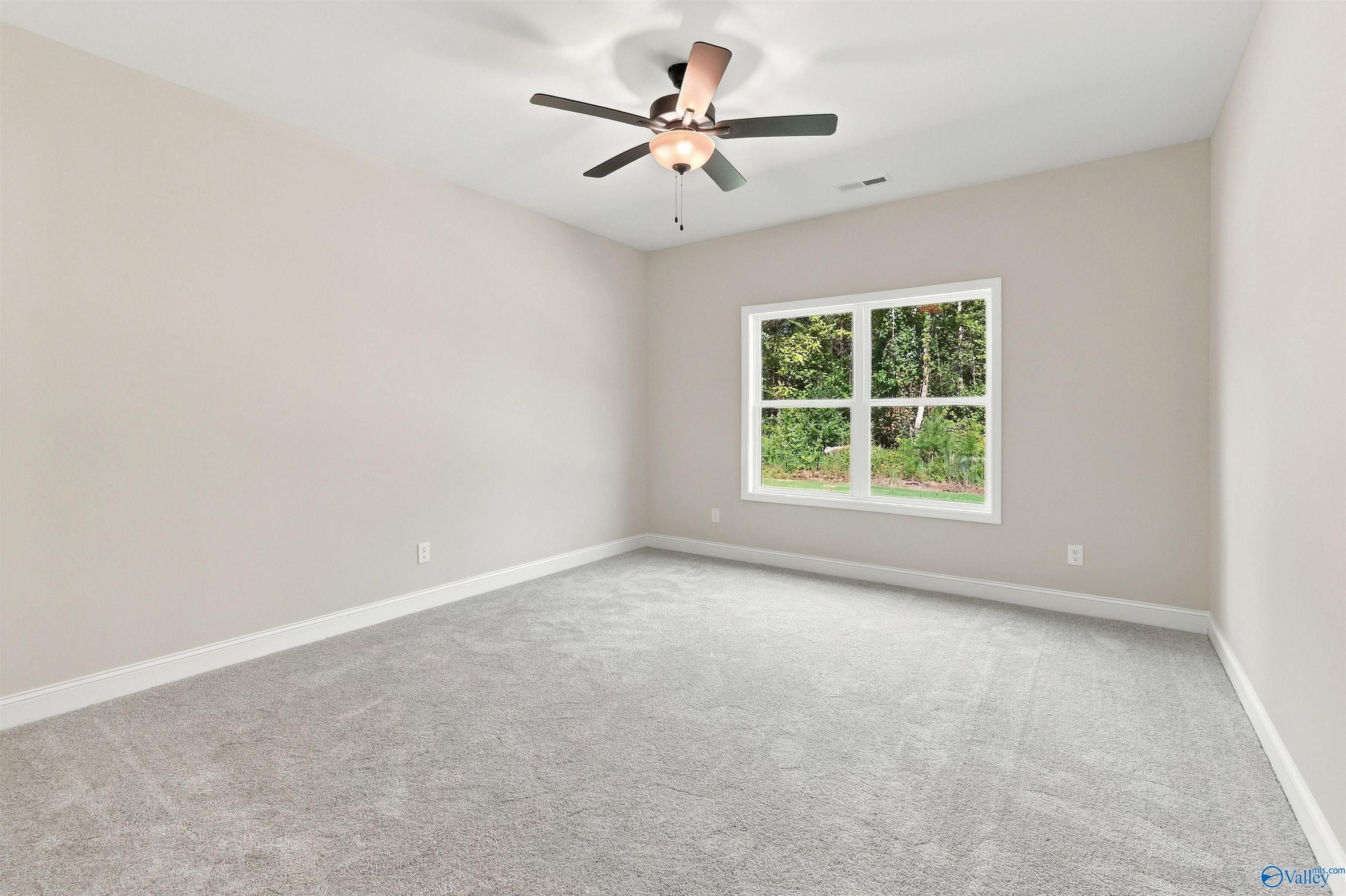 Bright, carpeted bedroom with ceiling fan in The Daphne floor plan by Davidson Homes in Spragins Cove, Huntsville, Alabama.