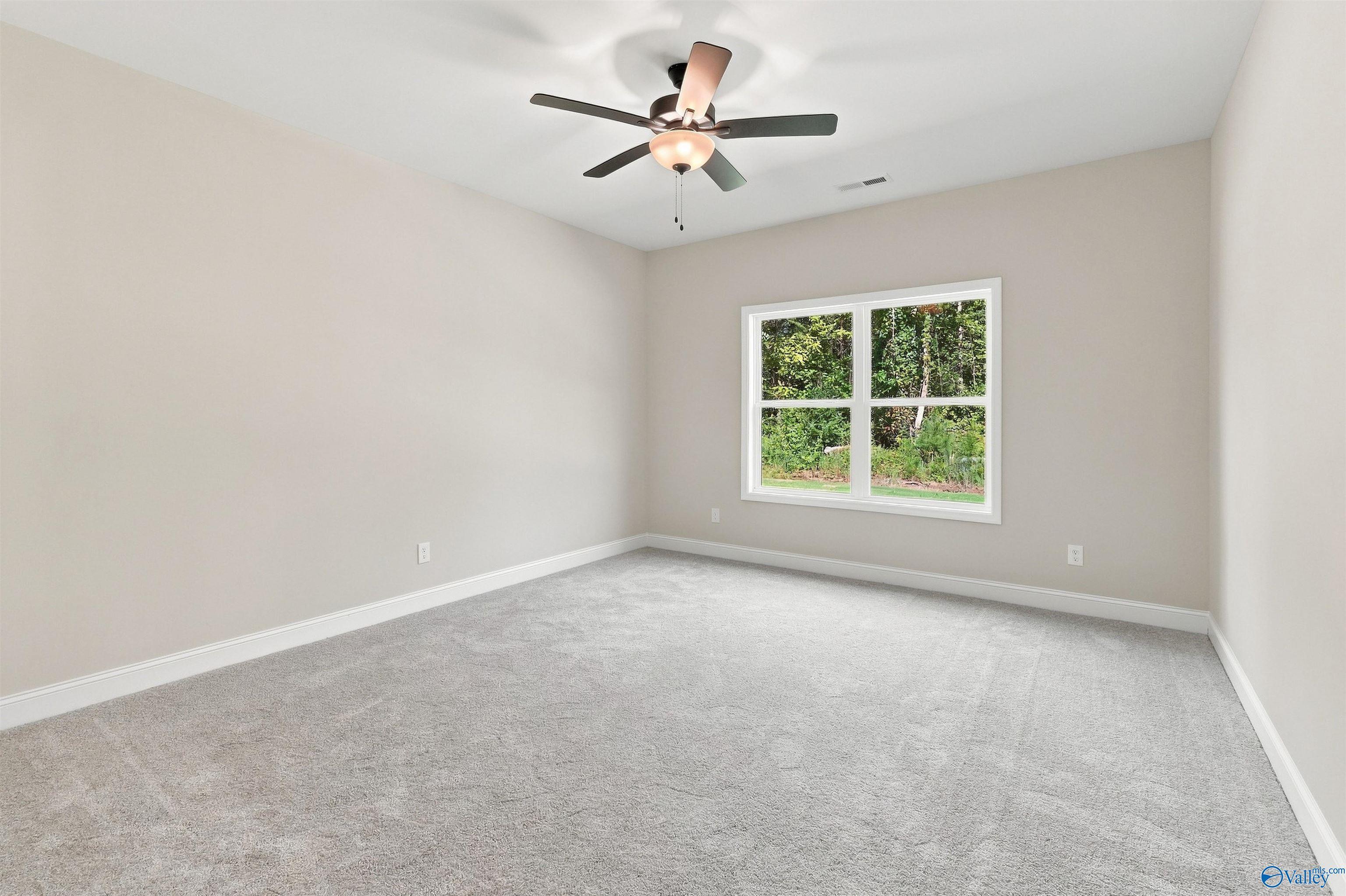 Bright, carpeted bedroom with ceiling fan in The Daphne floor plan by Davidson Homes in Spragins Cove, Huntsville, Alabama.